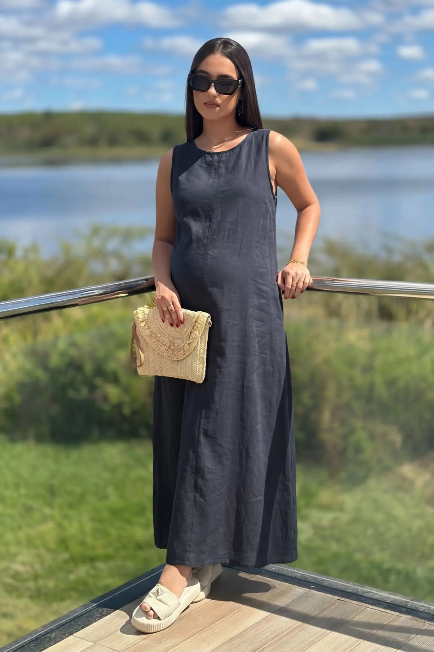 Sleeveless Pocketed Longline Hem Maternity Midi Dress Sleeveless pocketed longline hem maternity midi dress in dark blue with sleeveless design and longline hem, front view on pregnant model