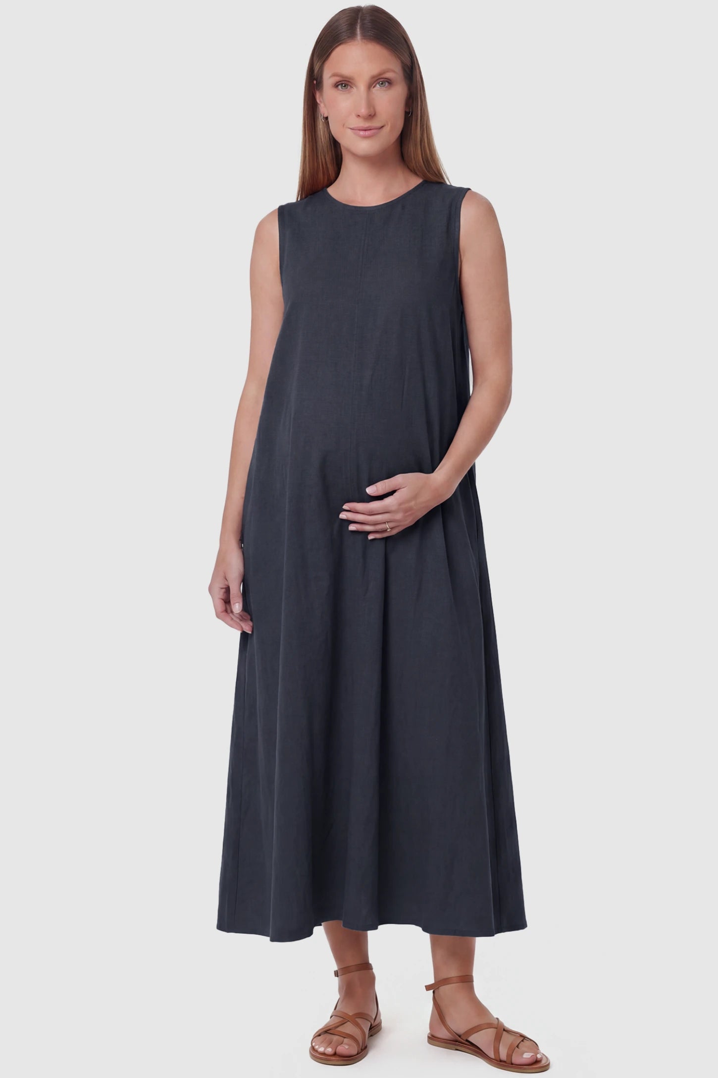 Sleeveless Pocketed Longline Hem Maternity Midi Dress Sleeveless pocketed longline hem maternity midi dress in dark blue with sleeveless design and longline hem, front view on pregnant model
