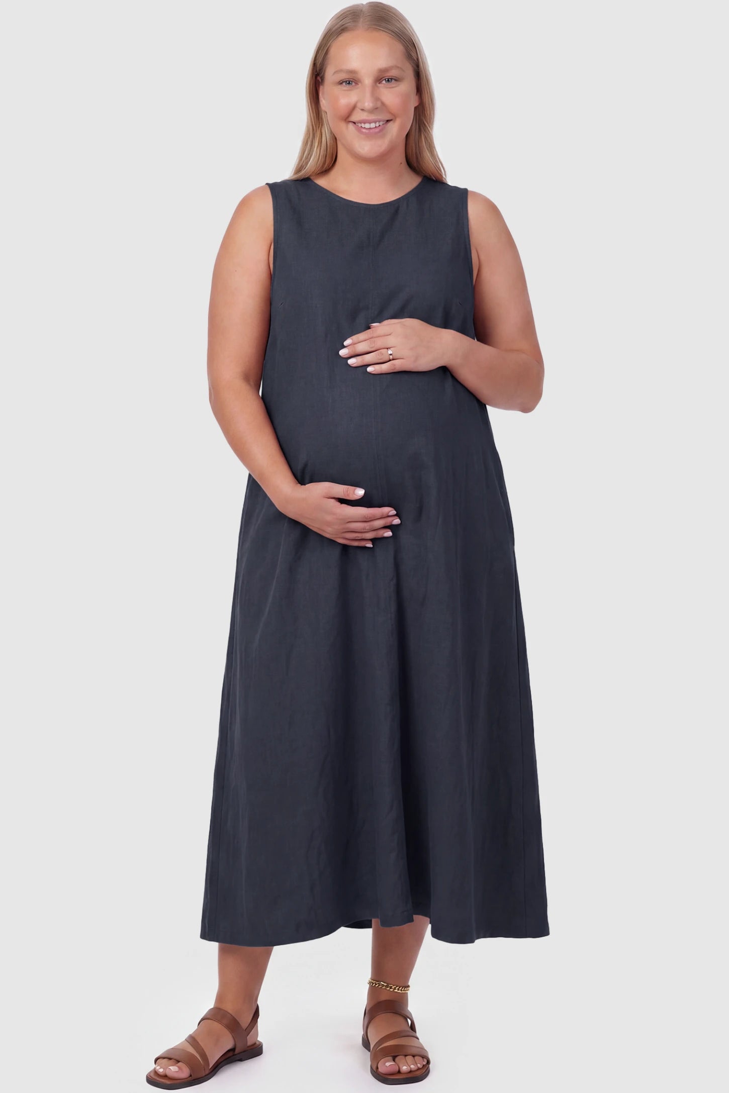 Sleeveless Pocketed Longline Hem Maternity Midi Dress Sleeveless pocketed longline hem maternity midi dress in dark blue with sleeveless design and longline hem, front view on plus-size model