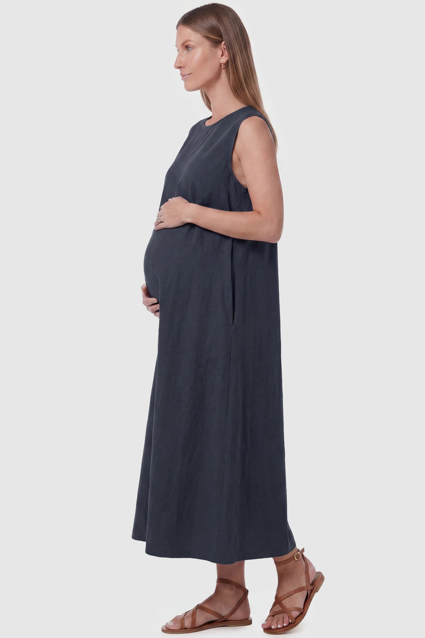 Sleeveless Pocketed Longline Hem Maternity Midi Dress Sleeveless pocketed longline hem maternity midi dress in dark blue with sleeveless design and side pocket, side view on pregnant model