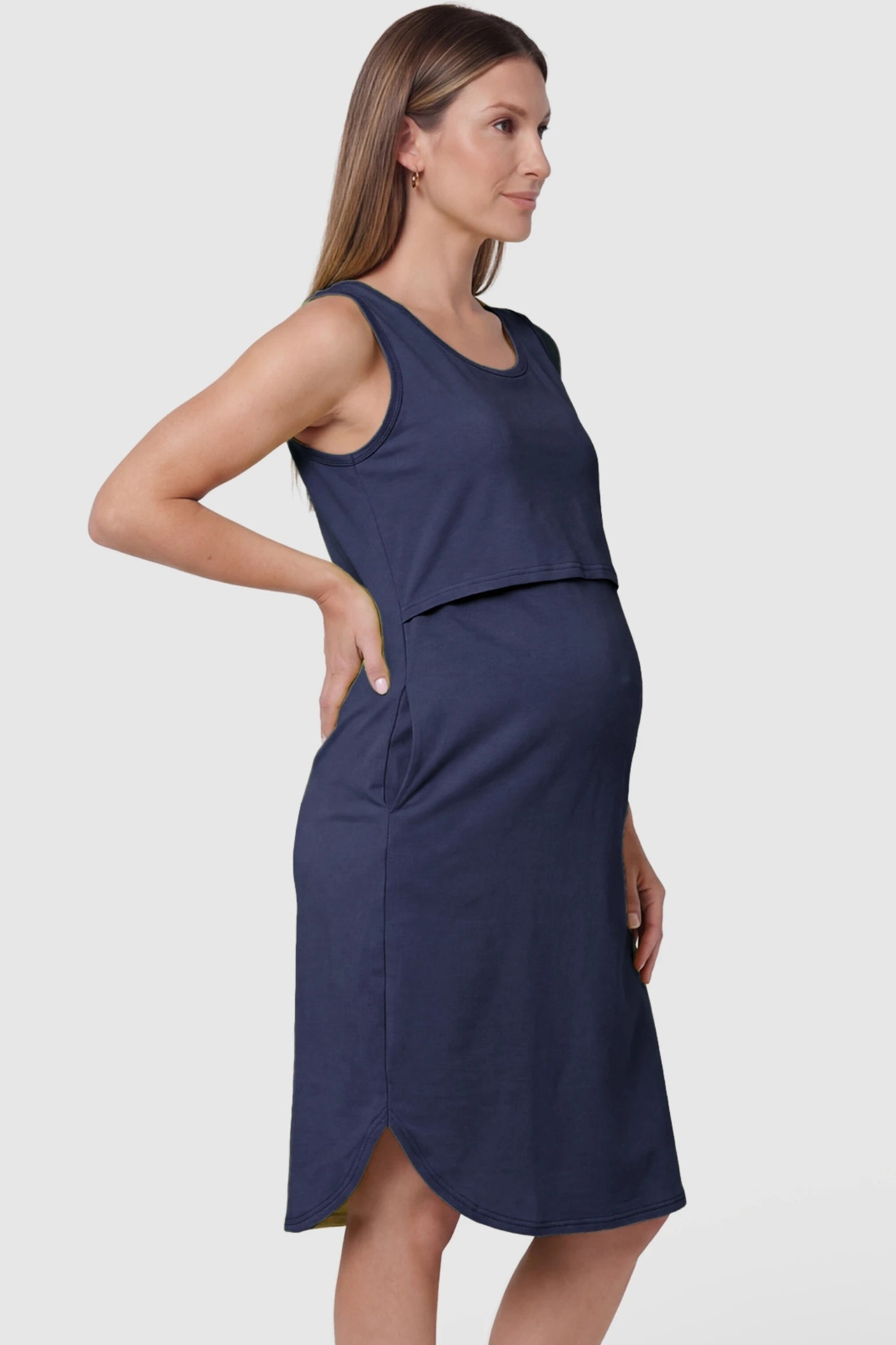Sleeveless High-Waisted Midi Maternity & Nursing Dress Sleeveless high-waisted midi maternity and nursing dress in dark blue featuring comfortable stretch cotton blend in side view on a pregnant model