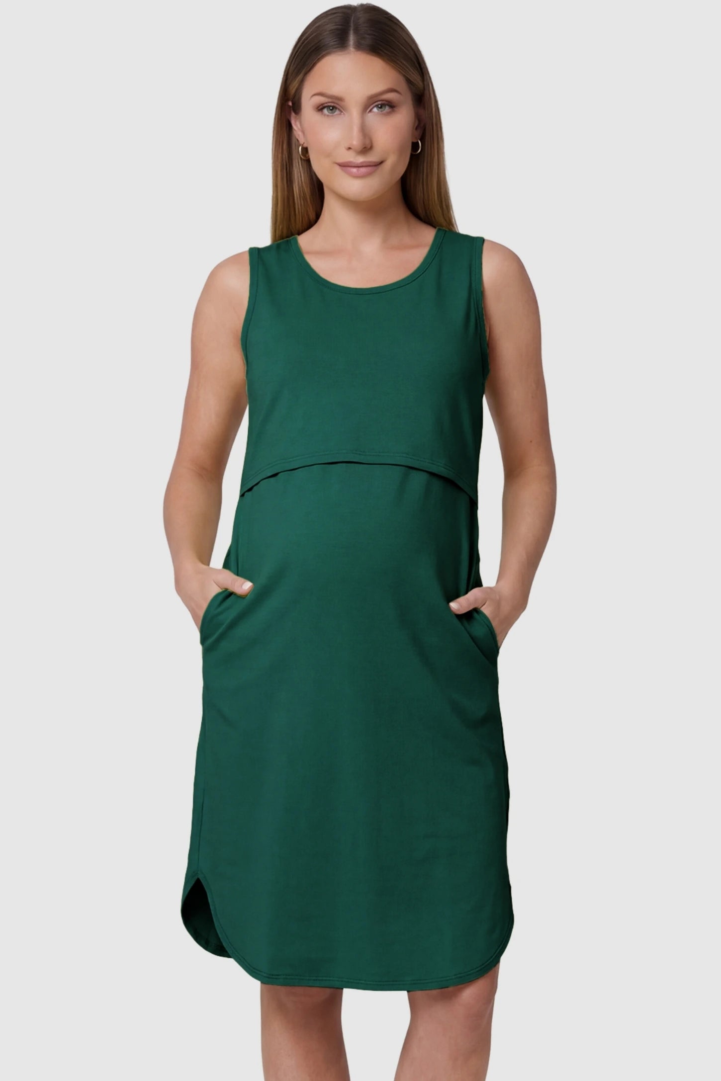 Sleeveless high-waisted midi maternity and nursing dress in green featuring functional side pockets in front view on a pregnant model