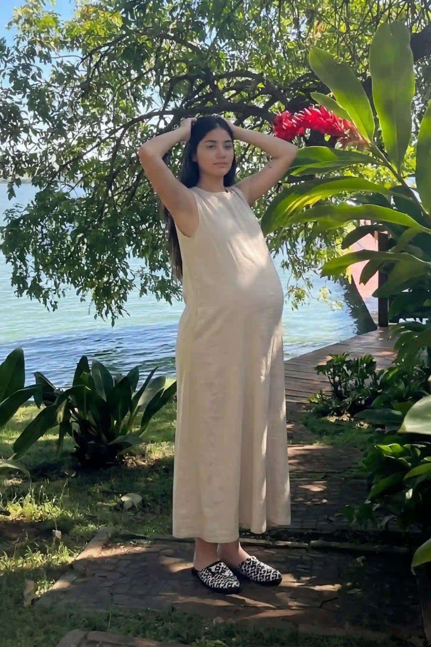 Sleeveless Pocketed Longline Hem Maternity Midi Dress Sleeveless pocketed longline hem maternity midi dress in khaki with sleeveless design and longline hem, side view on pregnant model