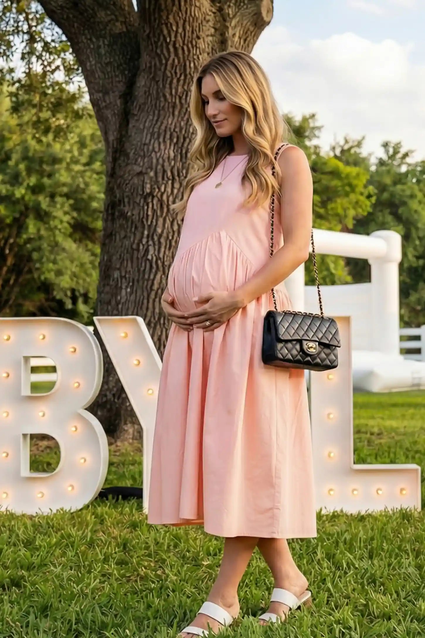 Sleeveless A-Line Maternity Midi Dress with Pockets Sleeveless A-line maternity midi dress with pockets in pink with sleeveless design and soft drape, side view on pregnant model