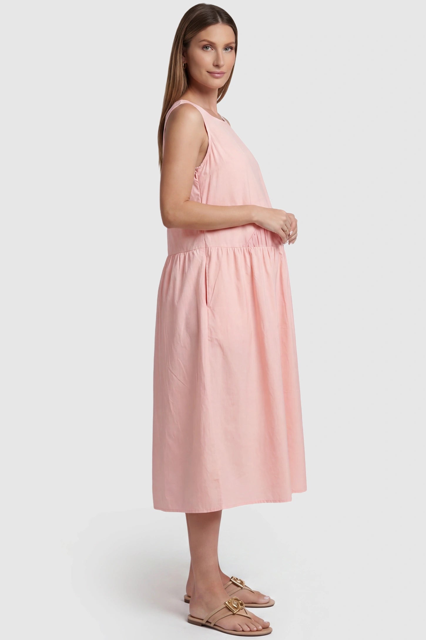 Sleeveless A-Line Maternity Midi Dress with Pockets Sleeveless A-line maternity midi dress with pockets in pink with sleeveless design and soft drape, side view on pregnant model