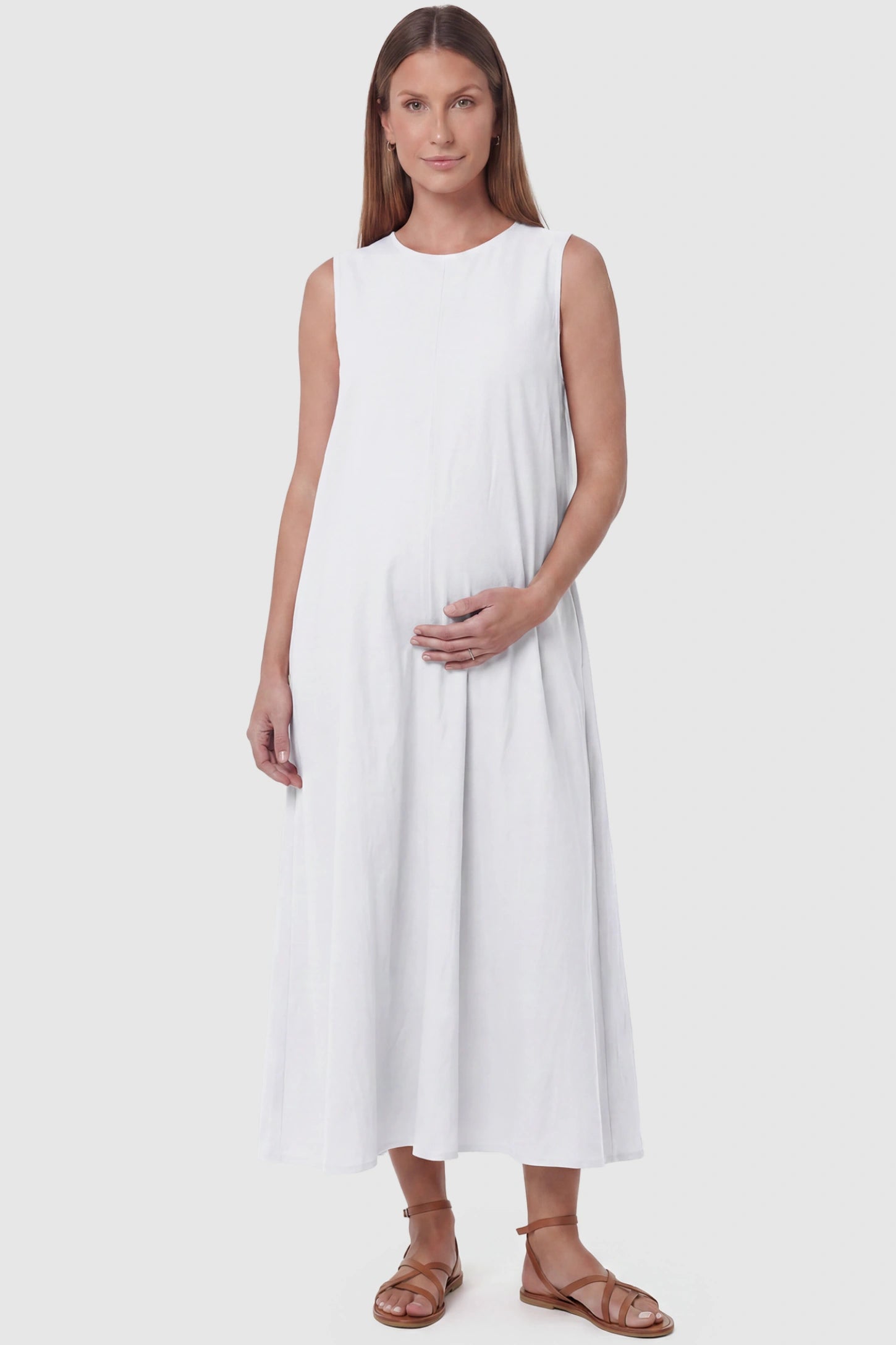 Sleeveless Pocketed Longline Hem Maternity Midi Dress Sleeveless pocketed longline hem maternity midi dress in white with sleeveless design and longline hem, front view on pregnant model