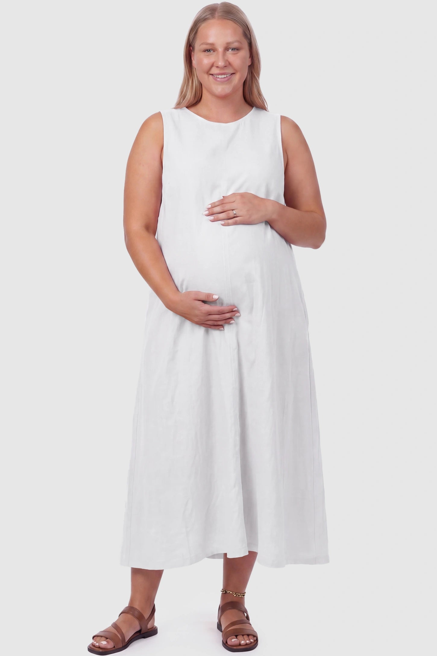 Sleeveless Pocketed Longline Hem Maternity Midi Dress Sleeveless pocketed longline hem maternity midi dress in white with sleeveless design and longline hem, front view on plus-size model