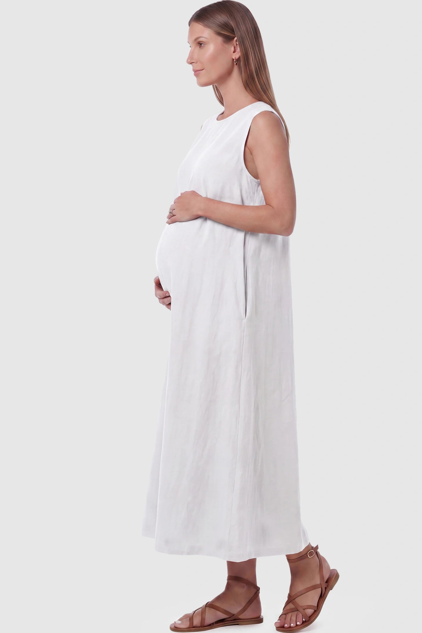 Sleeveless Pocketed Longline Hem Maternity Midi Dress Sleeveless pocketed longline hem maternity midi dress in white with sleeveless design and side pocket, side view on pregnant model