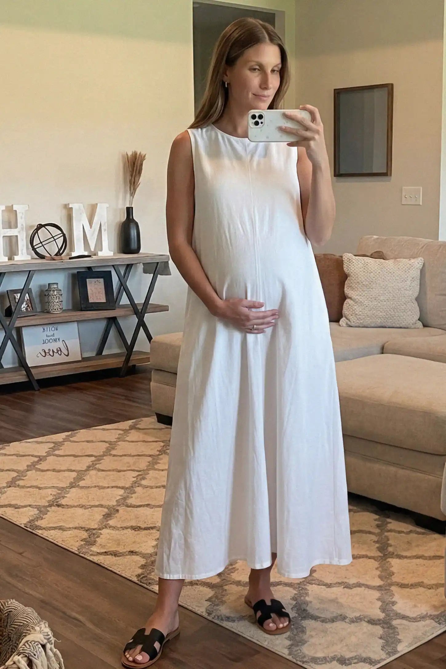 Sleeveless Pocketed Longline Hem Maternity Midi Dress Sleeveless pocketed longline hem maternity midi dress in white with sleeveless design and longline hem, front view on pregnant model