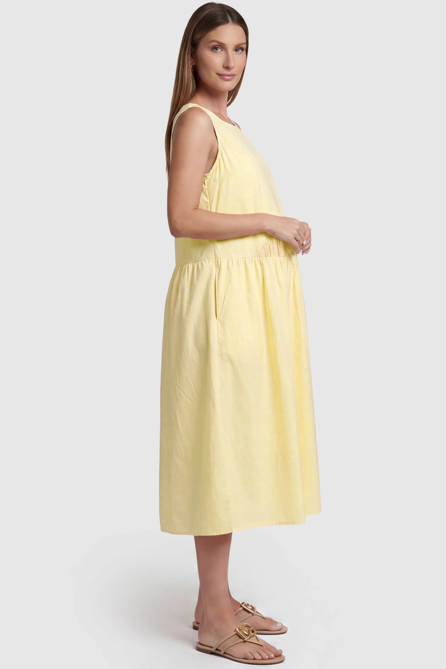Sleeveless A-Line Maternity Midi Dress with Pockets Sleeveless A-line maternity midi dress with pockets in yellow with sleeveless design and soft drape, side view on pregnant model