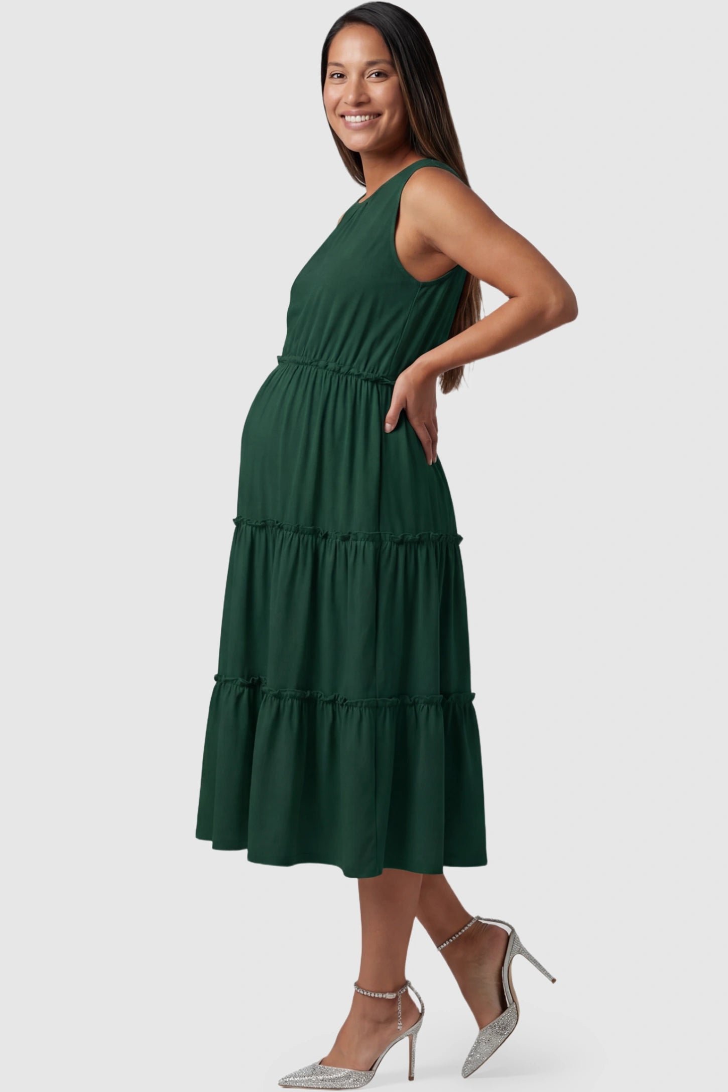 Solid Sleeveless Ruffle Tiered Maternity Midi Dress in dark green featuring a ruffle tiered skirt on a pregnant model showing side.