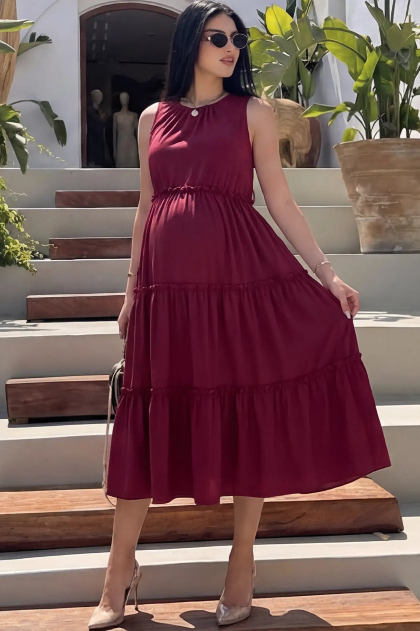 Solid Sleeveless Ruffle Tiered Maternity Midi Dress Solid Sleeveless Ruffle Tiered Maternity Midi Dress in wine red featuring a ruffle tiered skirt on a pregnant model.