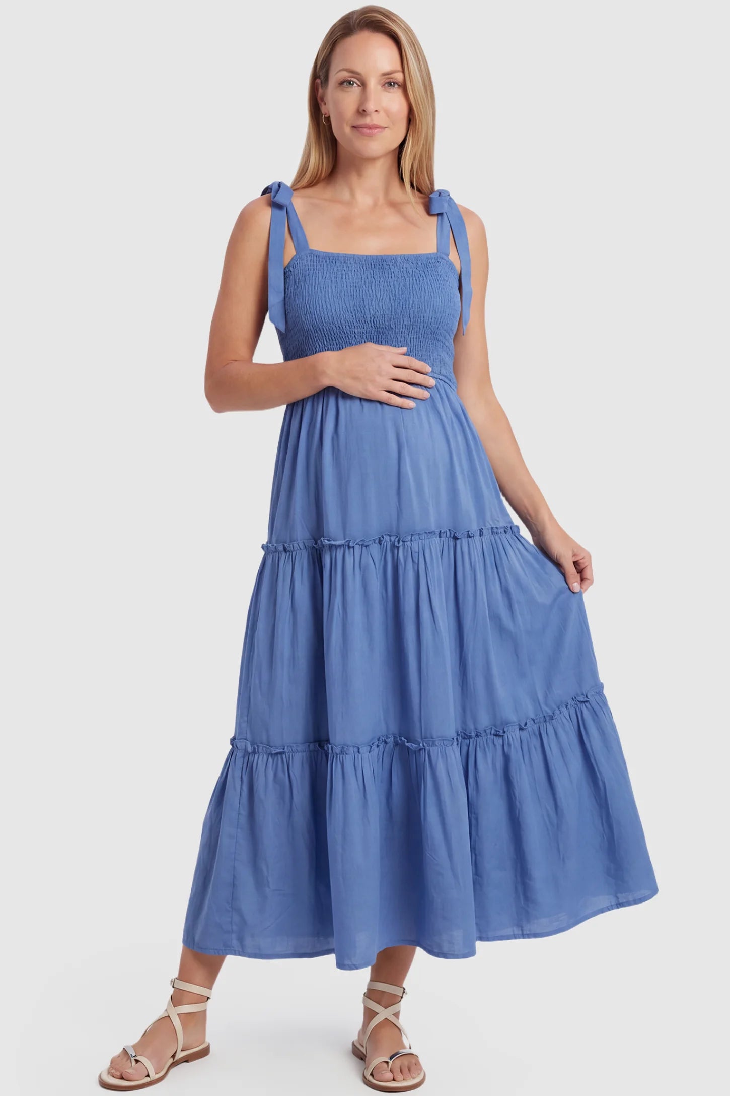 Smocked Square Neck Tiered Maternity Midi Dress Smocked square neck tiered maternity midi dress in blue with square neckline, smocked bodice, and adjustable tie straps, front view on postpartum model