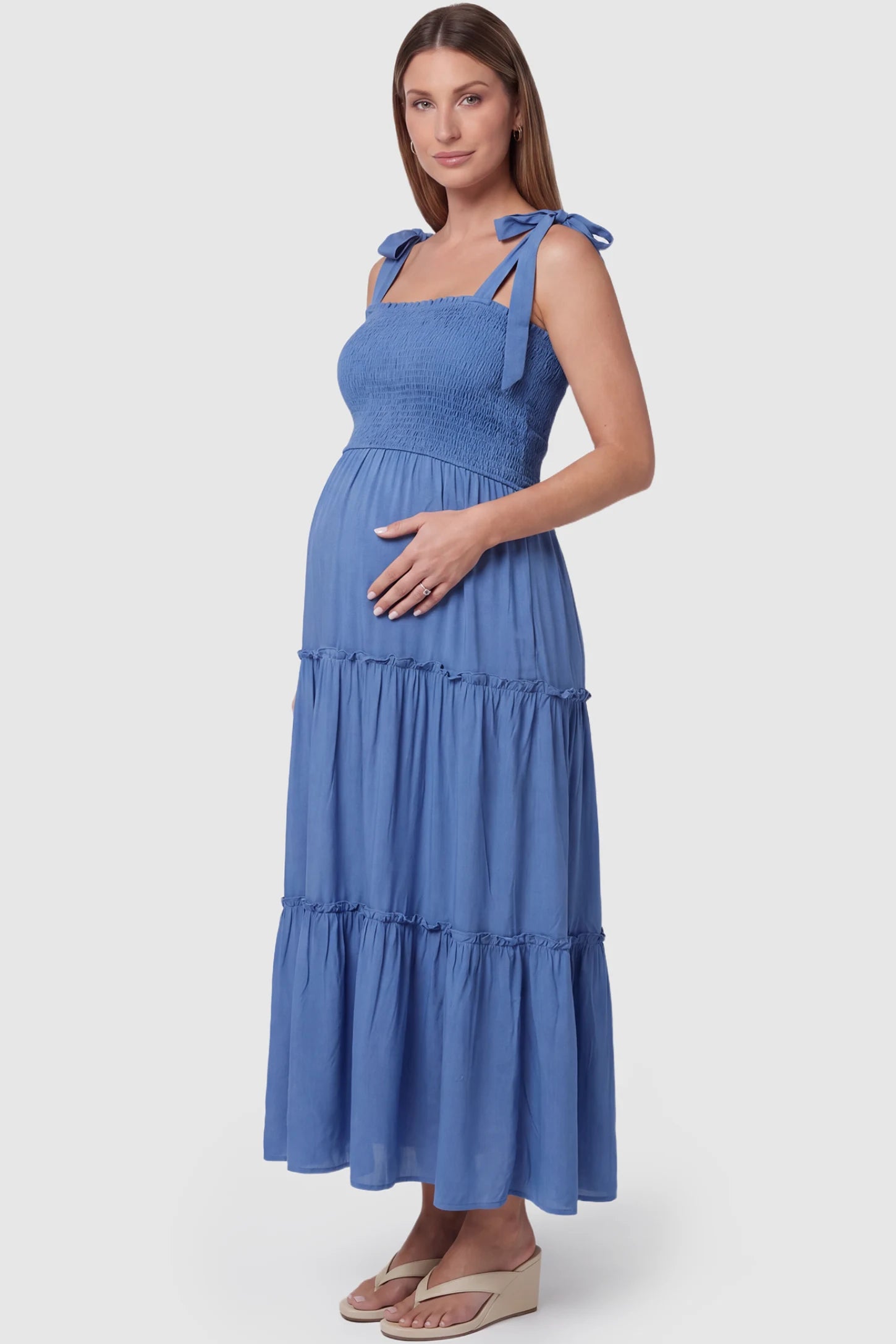 Smocked Square Neck Tiered Maternity Midi Dress Smocked square neck tiered maternity midi dress in blue with adjustable tie strap & tiered skirt, side view on pregnant model