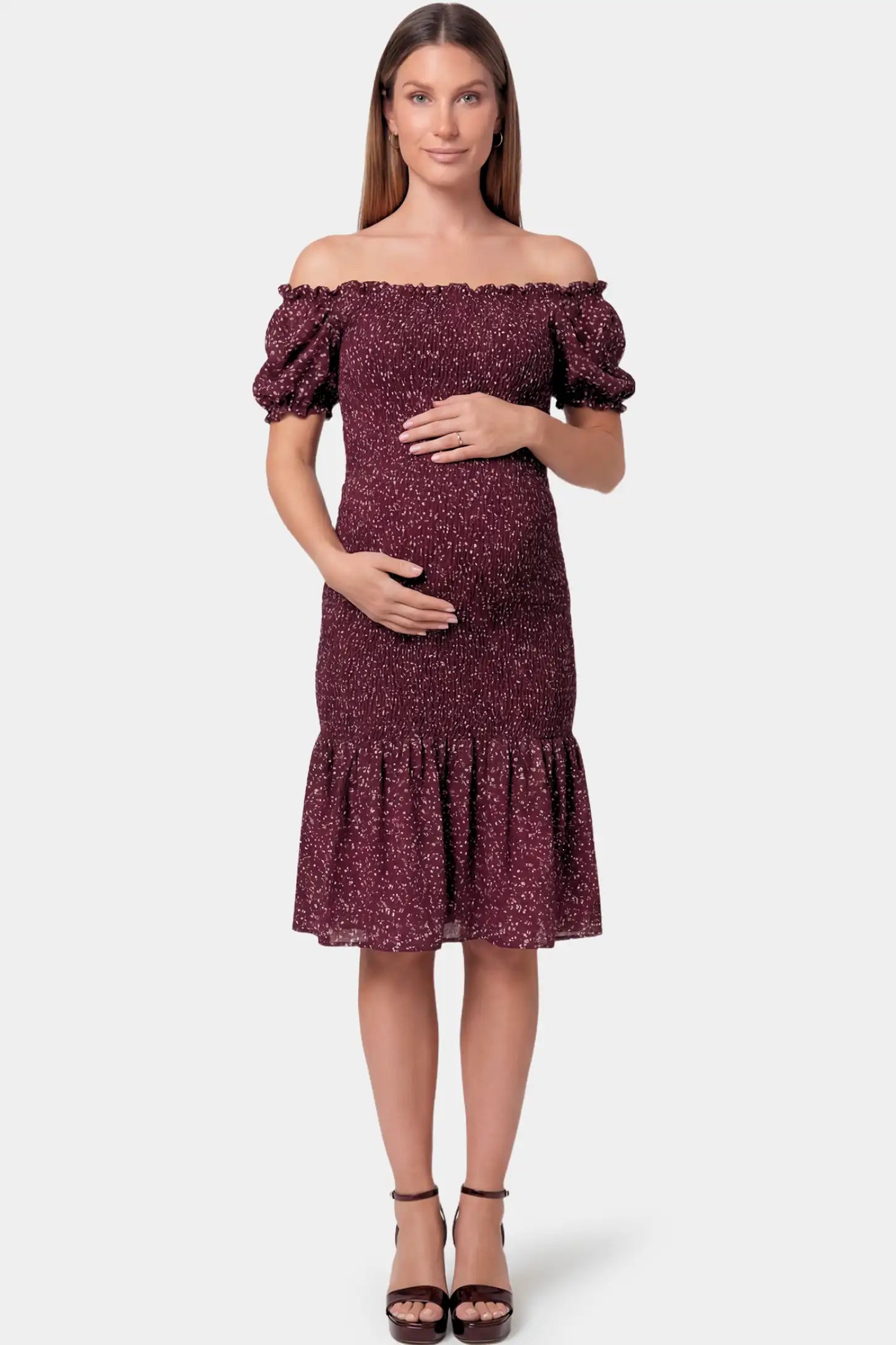 Short Puff Sleeve Smocked Maternity Midi Dress in burgundy floral featuring off shoulder neckline and ruffle hem on a pregnant model.