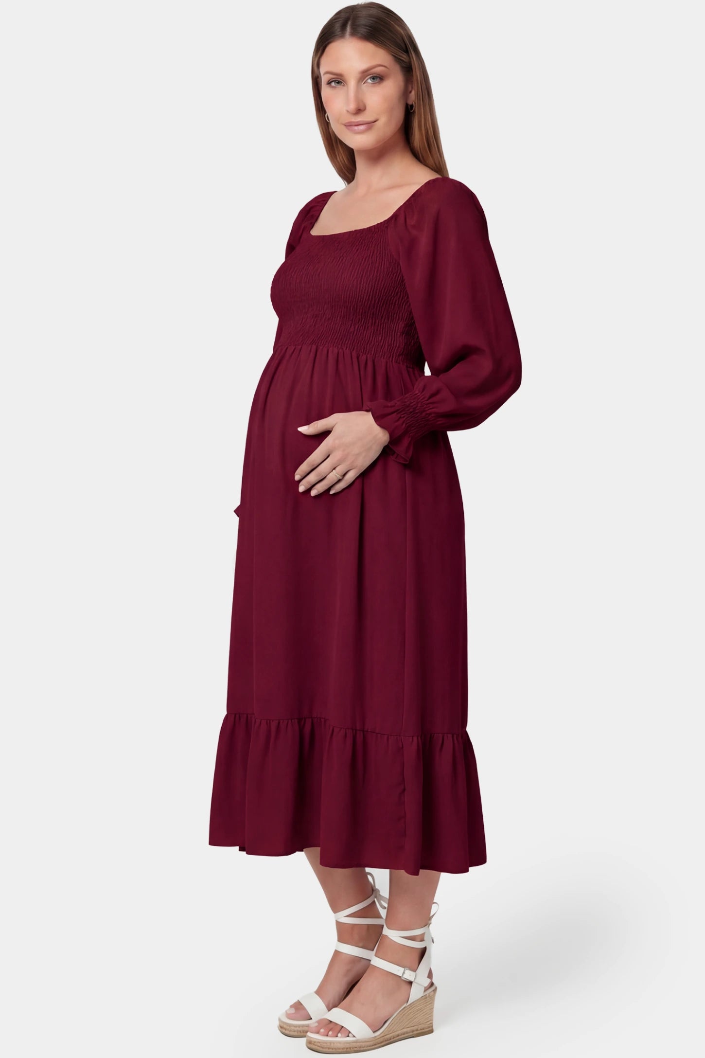 Smocked square neck ruffle hem midi maternity dress in burgundy featuring smocked bodice in side view on a pregnant model