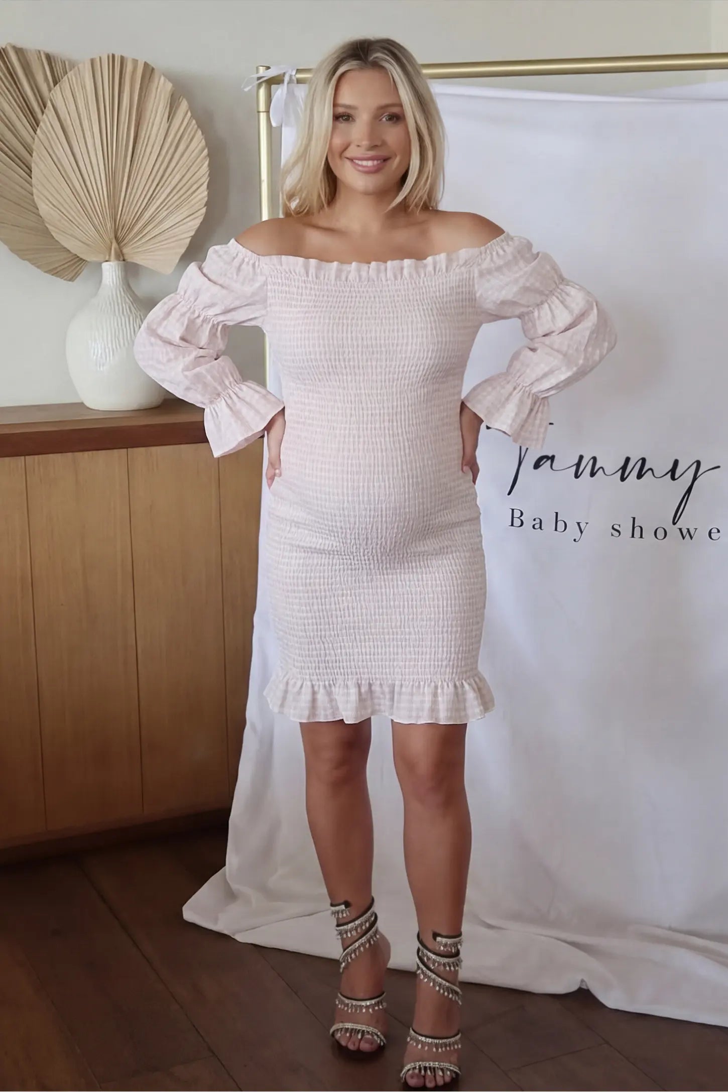 Smocked Off-Shoulder Bodycon Maternity Short Dress Smocked off-shoulder bodycon maternity short dress in white pink gingham with smocked bodice detail, front view on pregnant model