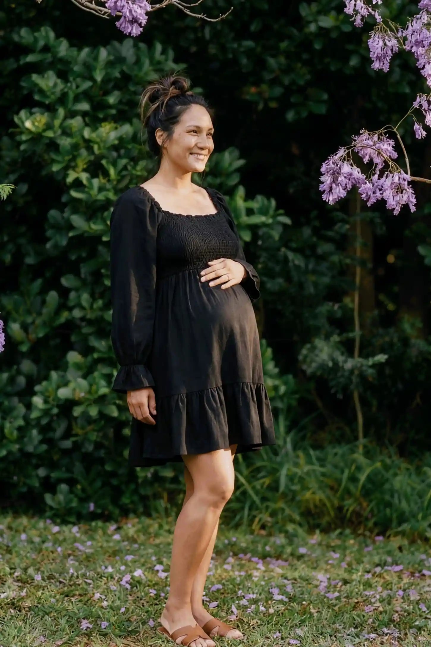 Smocked Chiffon A-Line Maternity Mini Dress Smocked Chiffon A-Line Maternity Mini Dress in Black featuring a flexible smocked bust on a side-profile pregnant model.
