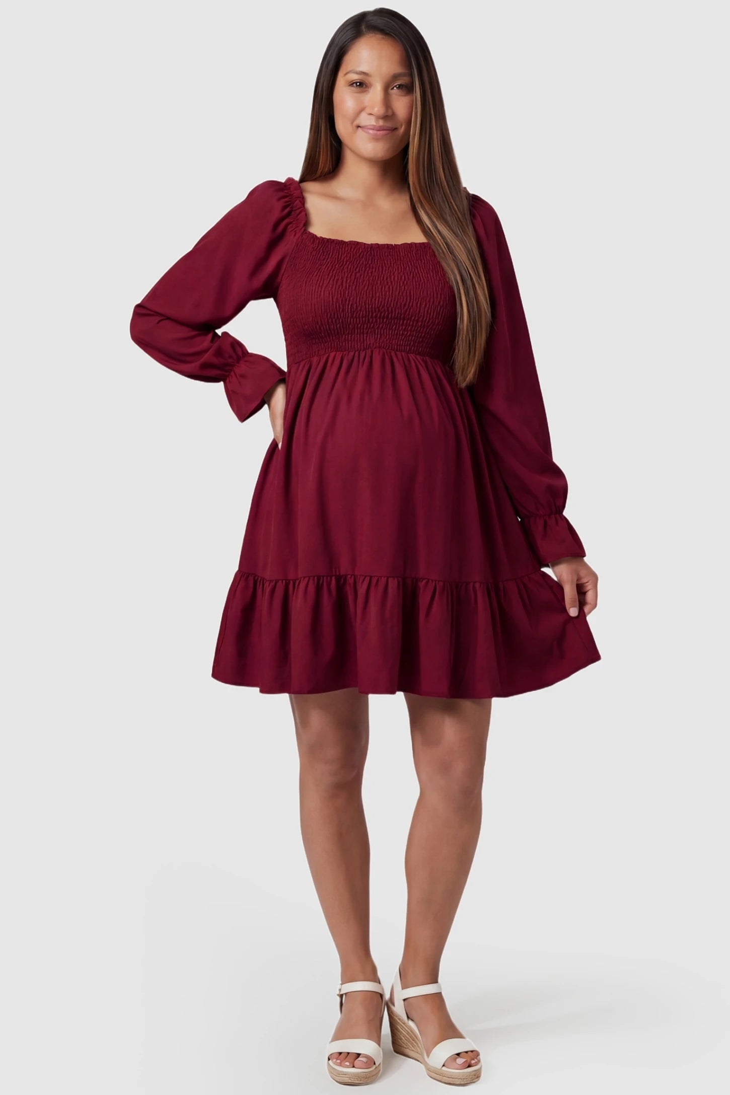 Smocked Chiffon A-Line Maternity Mini Dress Smocked Chiffon A-Line Maternity Mini Dress in Burgundy with a ruffled edge trend on a pregnant model, front view.
