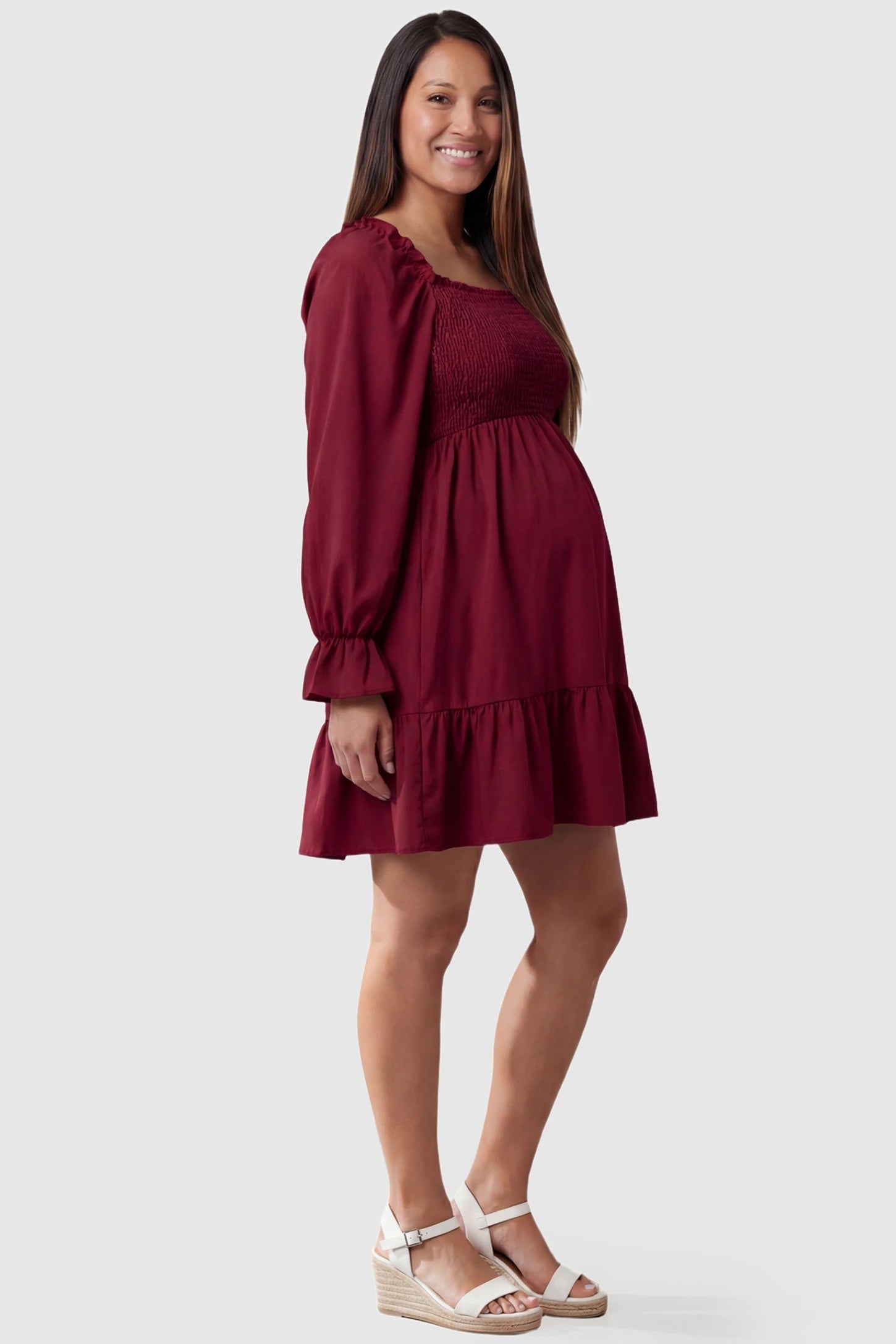 Smocked Chiffon A-Line Maternity Mini Dress Burgundy Smocked Chiffon A-Line Maternity Mini Dress featuring breathable chiffon on a pregnant model, side profile.