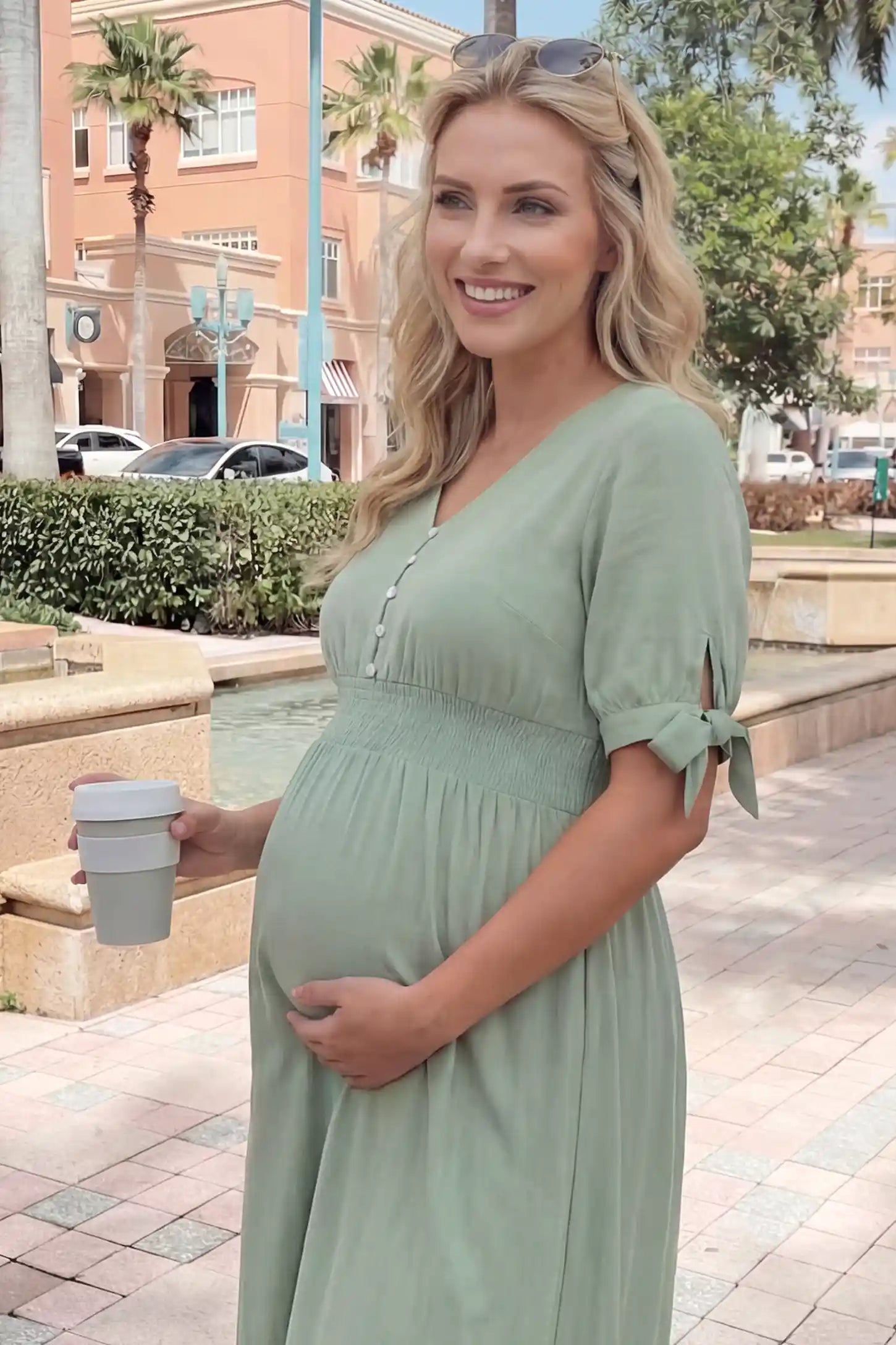 V-neck smocked waist A-line maxi maternity dress in mint green featuring button detail and V-neckline in front view on a editorial lifestyle model