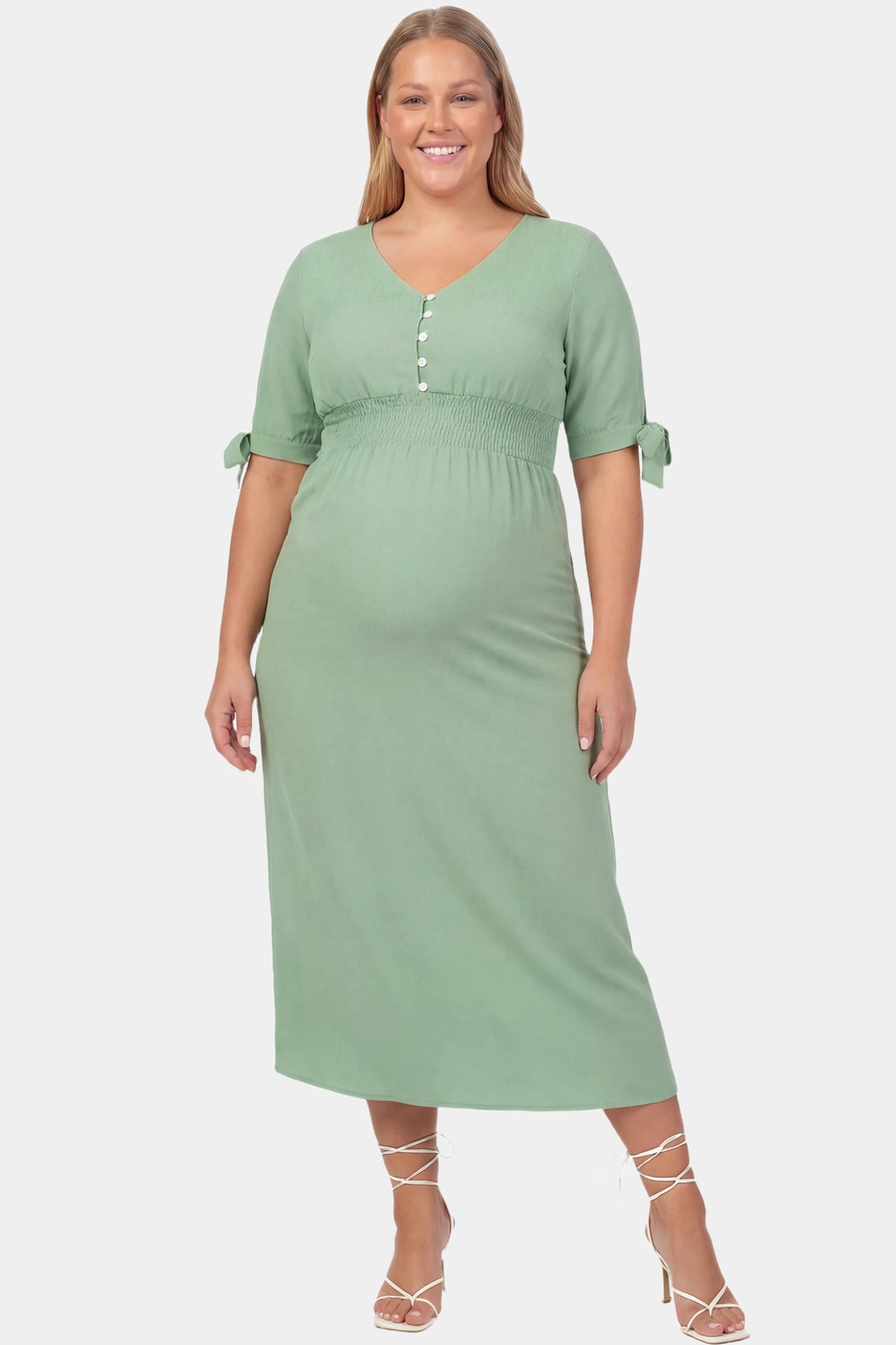 V-Neck Smocked Waist A-Line Maxi Maternity Dress V-neck smocked waist A-line maxi maternity dress in mint green featuring button detail and V-neckline in front view on a plus-size model