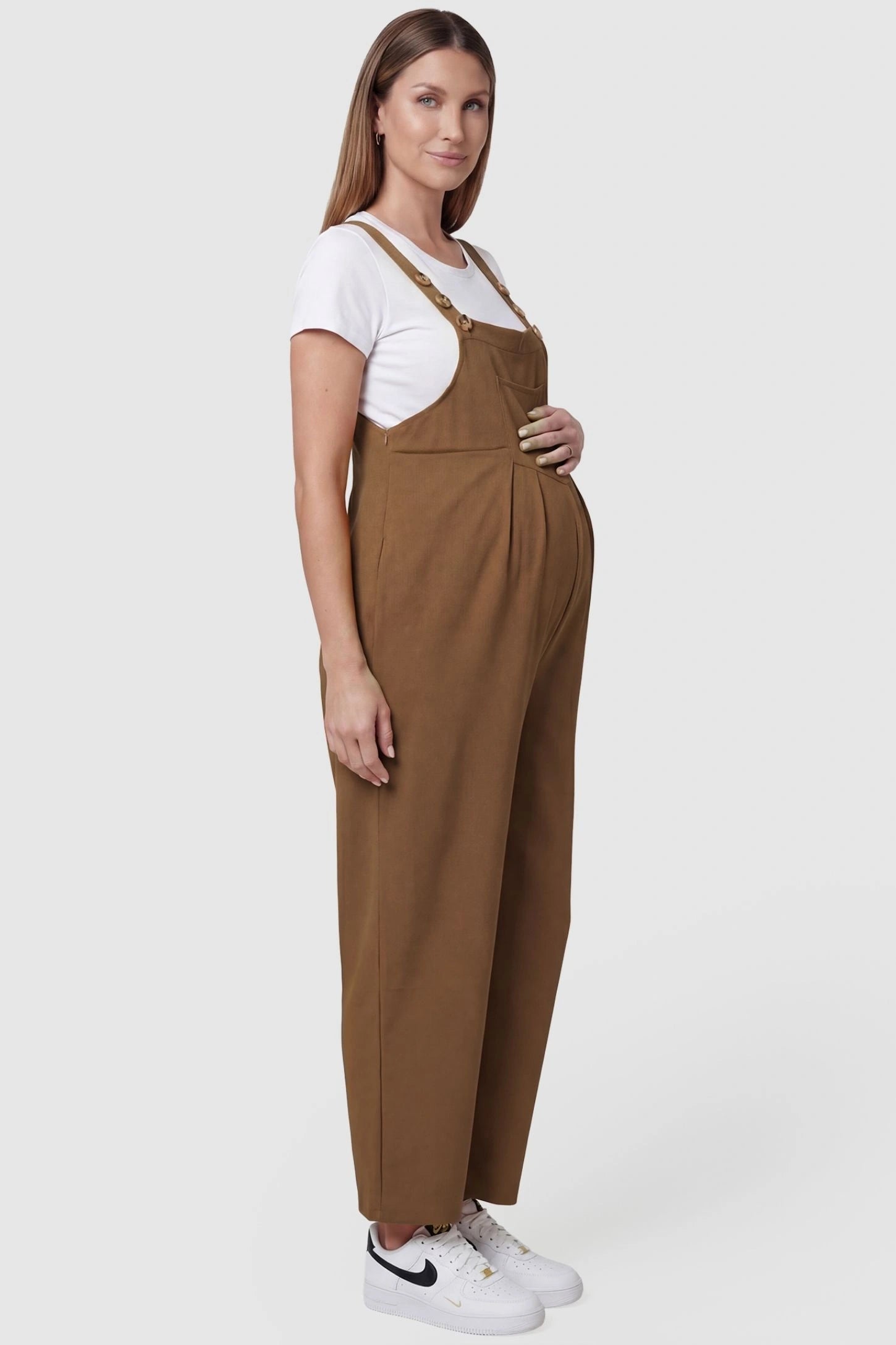 Full-Length Pocketed Maternity Jumpsuit Full-Length Pocketed Maternity Jumpsuit in Camel featuring adjustable straps and a relaxed fit on a pregnant model, side view.