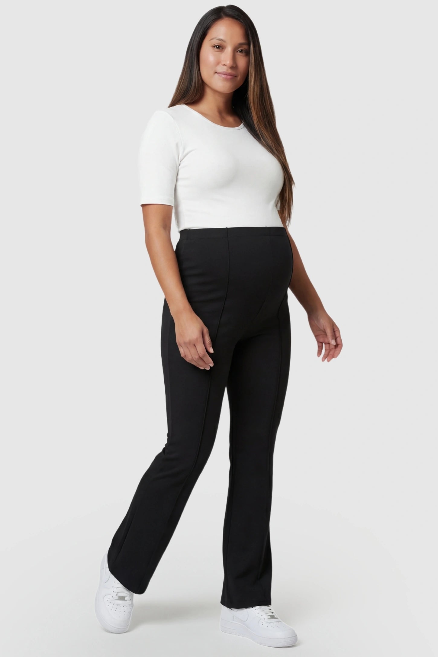 Buttery Soft High Waisted Flare Leg Maternity Pants in black featuring a supportive tummy panel on a pregnant model, full body shot.