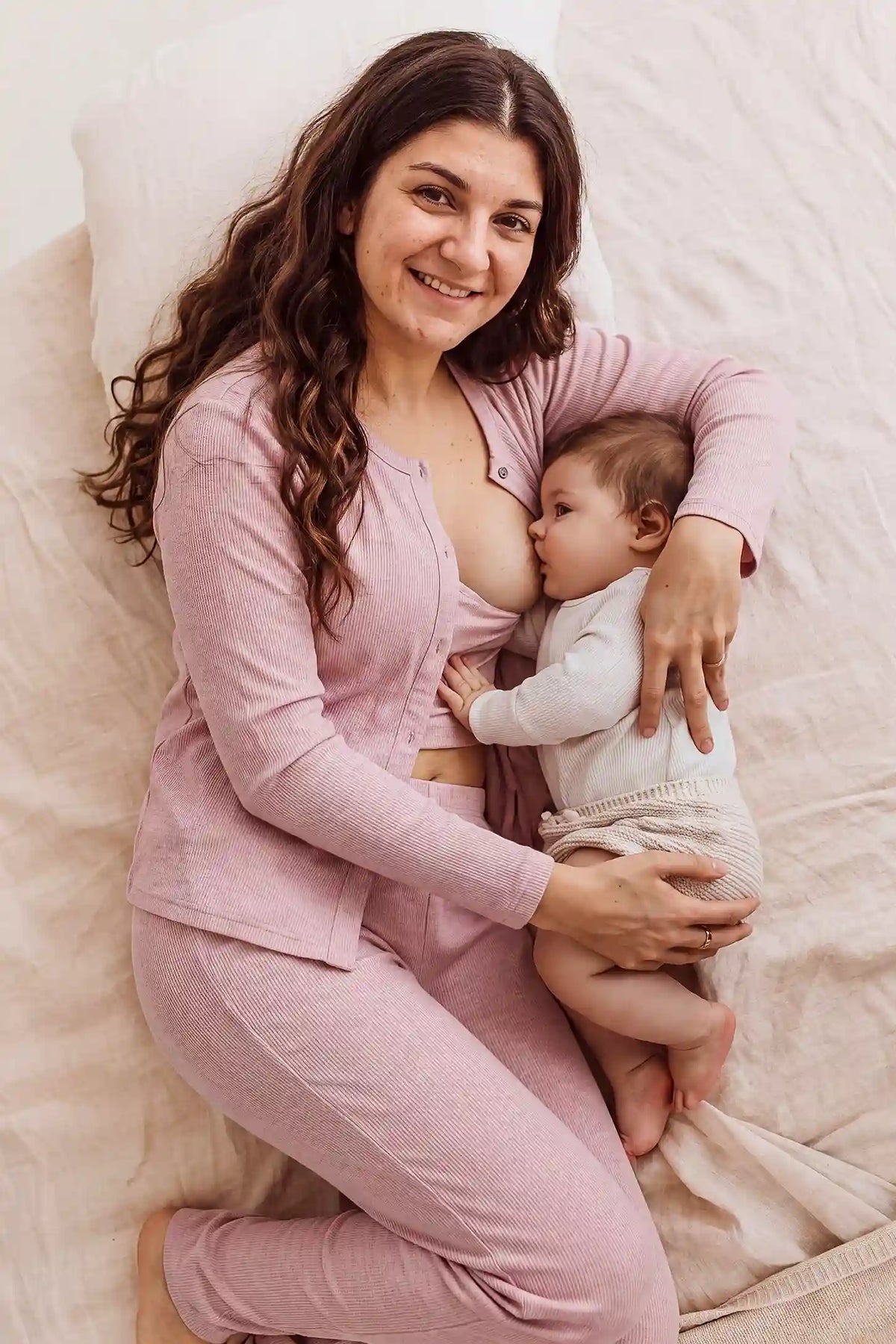 Soft Rib Knit Maternity & Nursing PJ Set with Cami, Cardigan & Pants Soft Rib Knit Maternity & Nursing Pajama Set with Cami, Cardigan & Pants in Soft Pink featuring comfortable long sleeve cardigan, gentle bump support, and cozy nursing sleepwear style on a pregnant model in a bedroom setting.