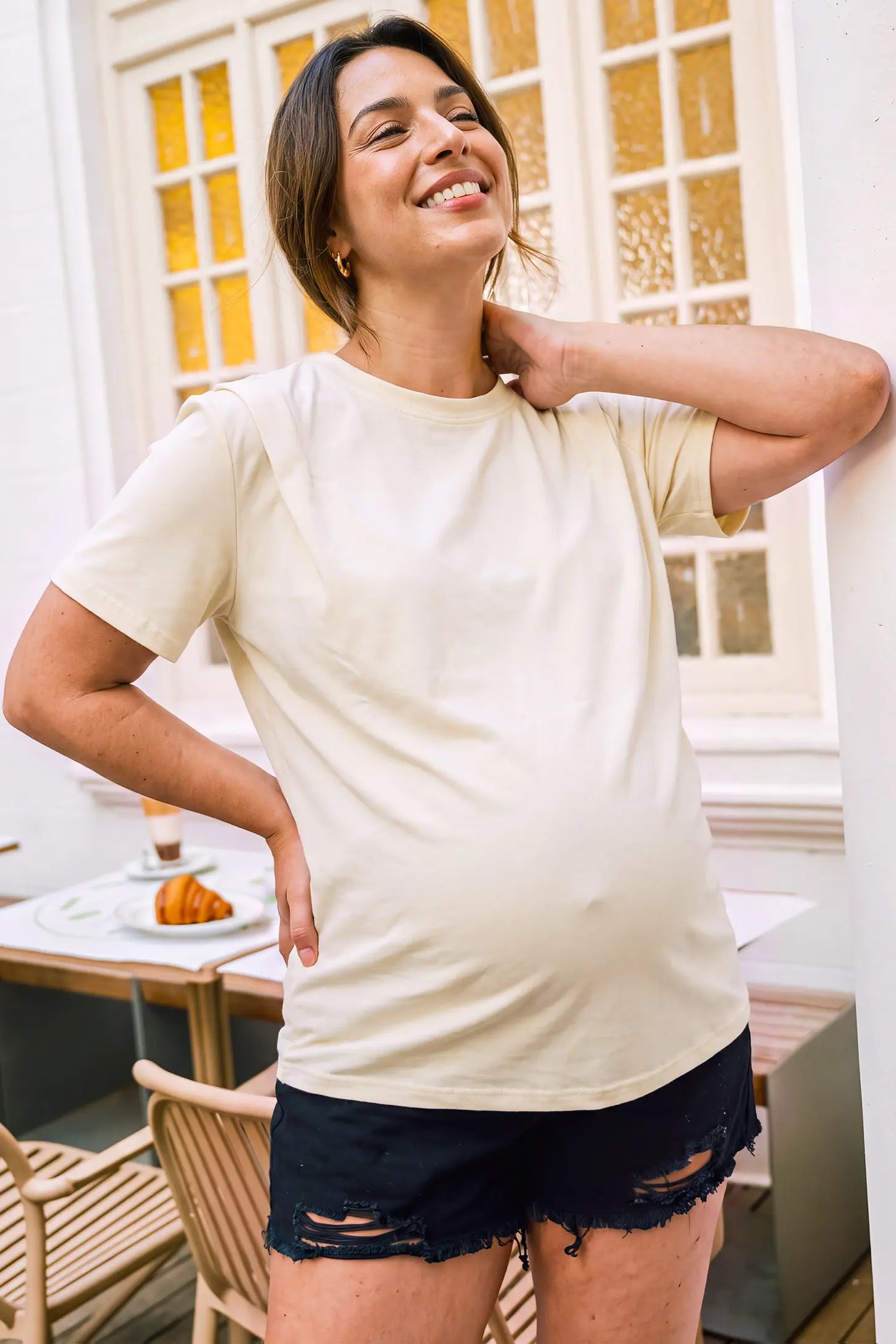 Solid Round Neck Short Sleeve Maternity Top in Beige featuring a minimalist solid design, soft-touch fabric, and a comfortable maternity fit on a pregnant model in an editorial lifestyle setting.