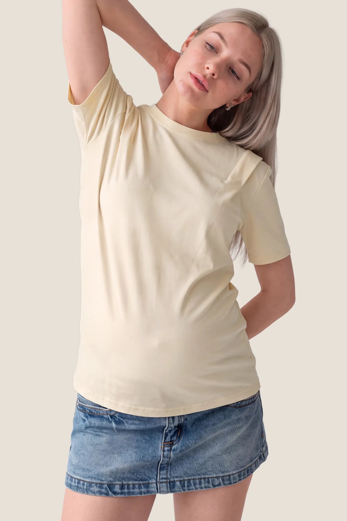 Solid Round Neck Short Sleeve Maternity Top Solid Round Neck Short Sleeve Maternity Top in Beige featuring a round neckline, soft-touch fabric, short sleeves, and a comfortable maternity fit on a pregnant model, front view.