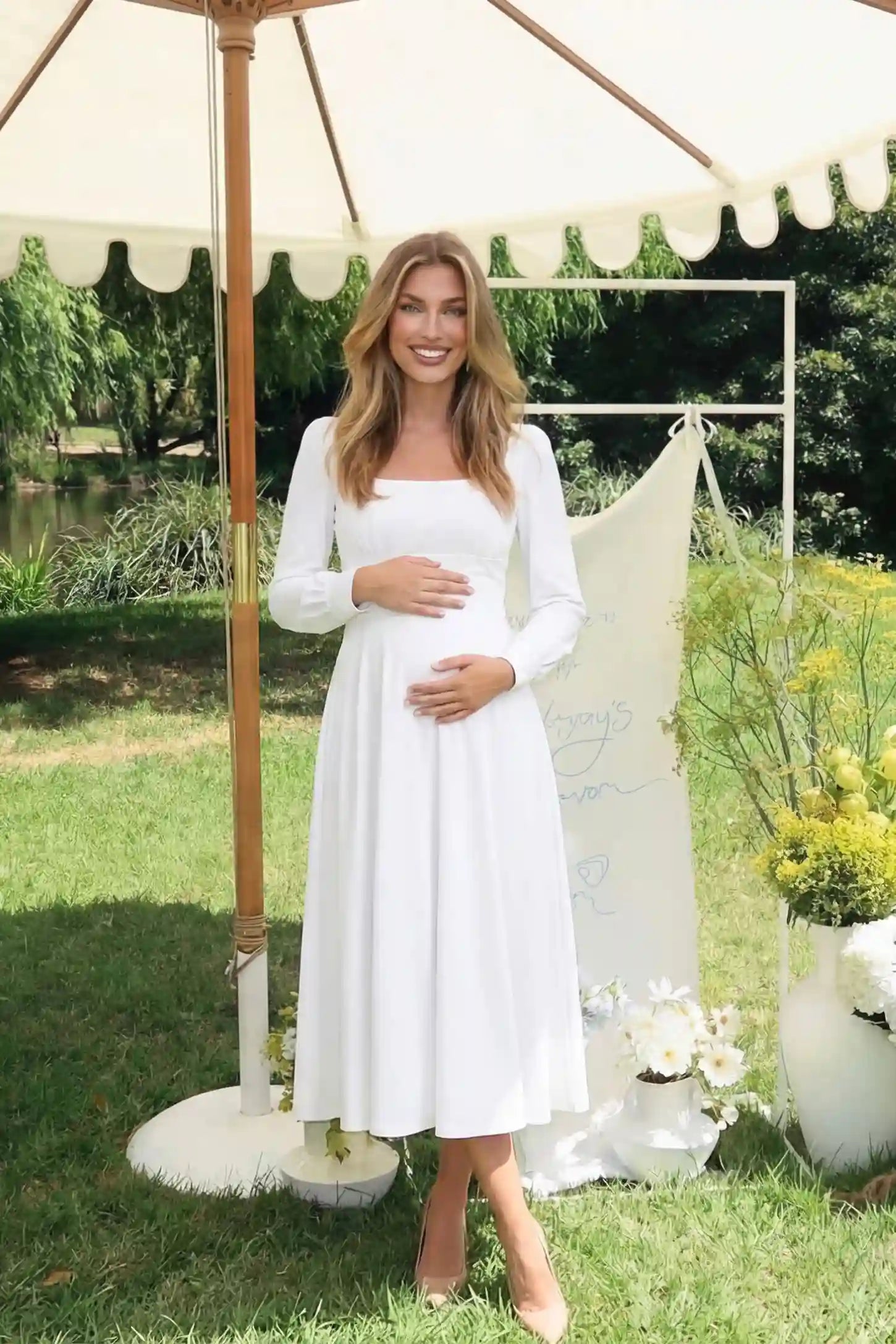 Square neck long sleeve A-line midi maternity dress in white featuring flowing silhouette in full body view on an editorial lifestyle model