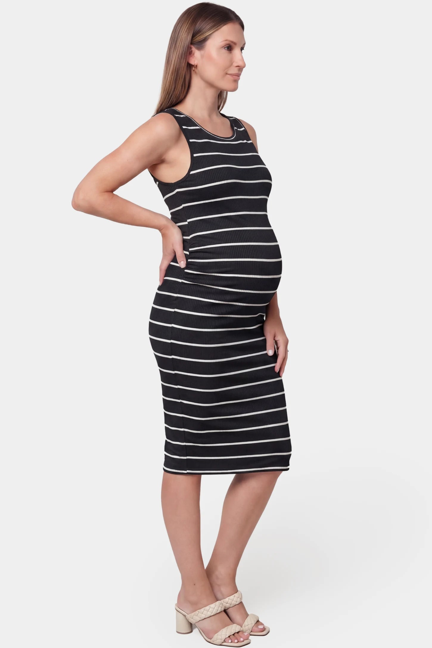 Striped sleeveless crew neck midi maternity dress in black featuring sleeveless cut in side view on a pregnant model