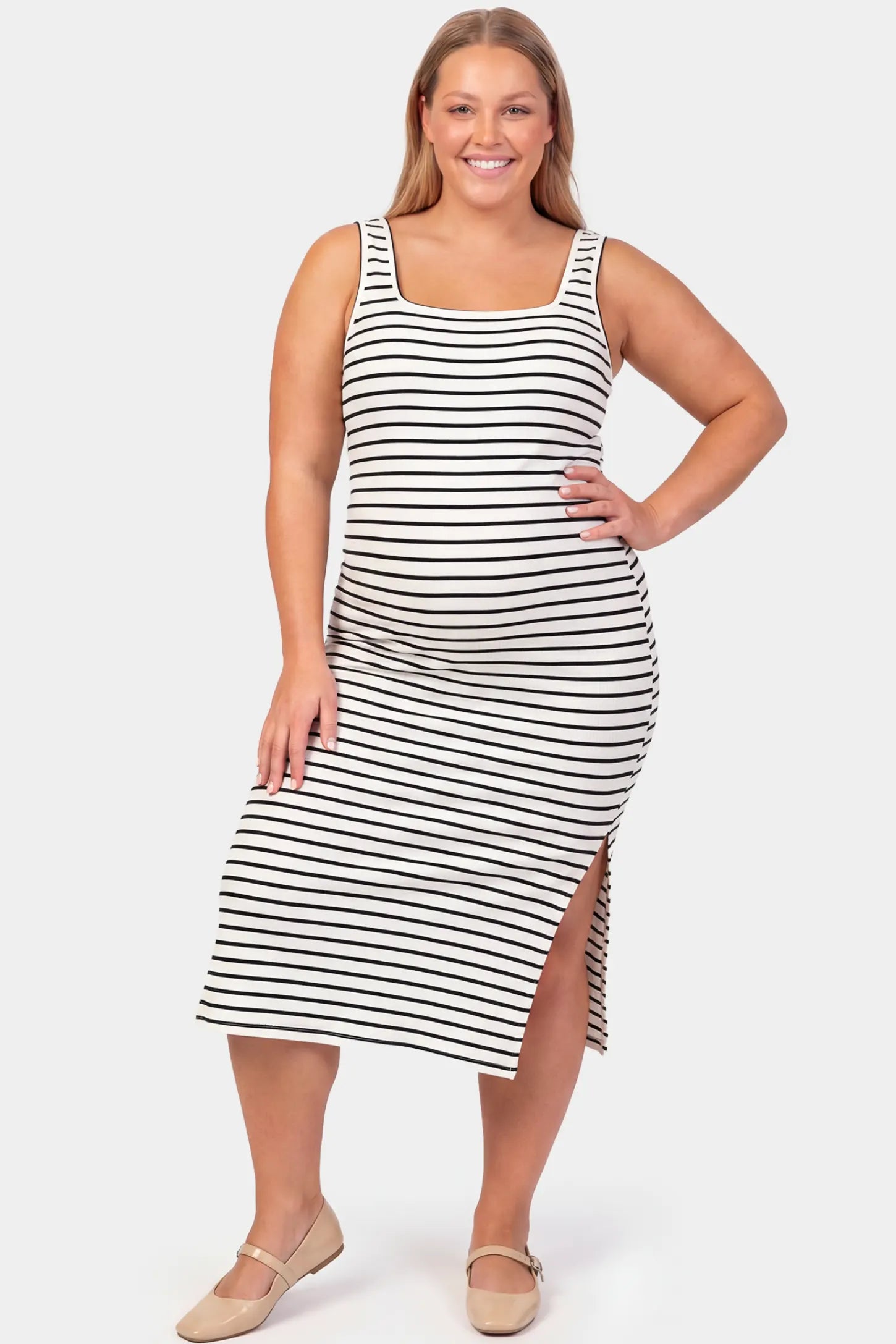 Striped Spaghetti Strap Side Slit Midi Maternity Dress Striped spaghetti strap side slit midi maternity dress in white featuring classic black-and-white stripes in front view on a plus-size model