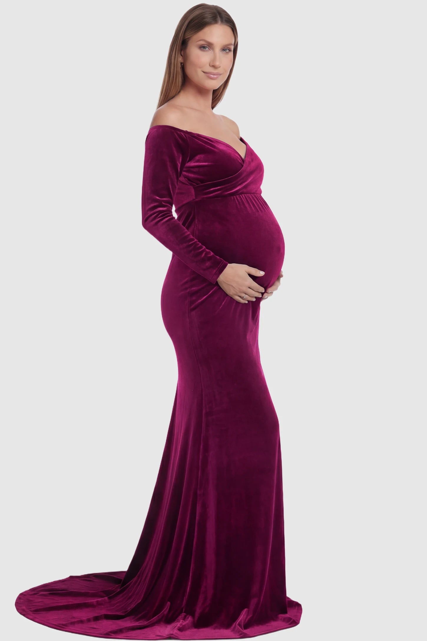 Velvet Long Fitted Sleeve Maternity Gown Velvet Long Fitted Sleeve Maternity Gown in burgundy featuring an off-shoulder sweetheart neckline, draped bust, empire waist, and mermaid skirt on pregnant model side view.