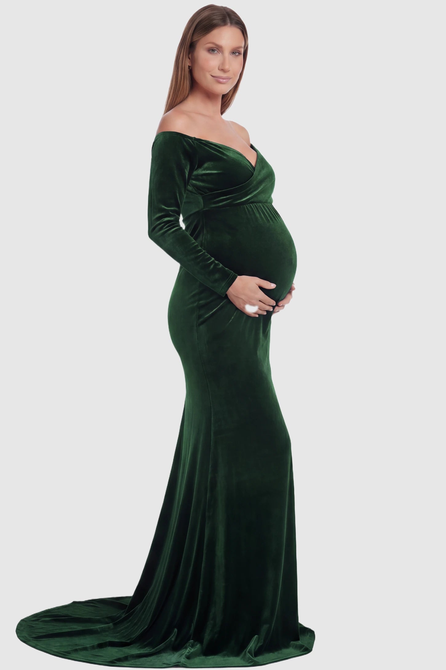 Velvet Long Fitted Sleeve Maternity Gown Velvet Long Fitted Sleeve Maternity Gown in green featuring an off-shoulder sweetheart neckline, draped bust, empire waist, and mermaid skirt on pregnant model side view.