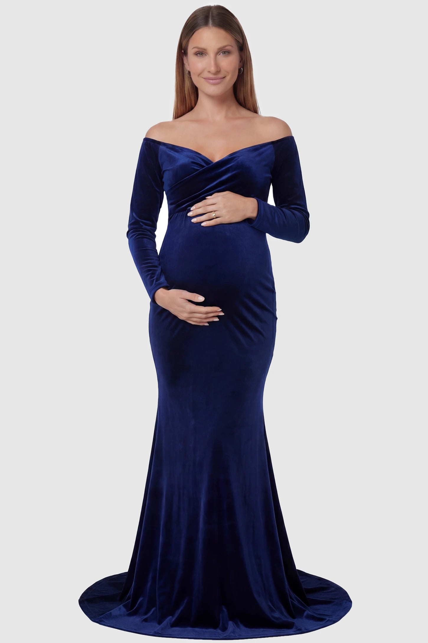 Velvet Long Fitted Sleeve Maternity Gown Velvet Long Fitted Sleeve Maternity Gown in navy blue featuring an off-shoulder sweetheart neckline, draped bust, empire waist, and mermaid skirt on pregnant model front view.