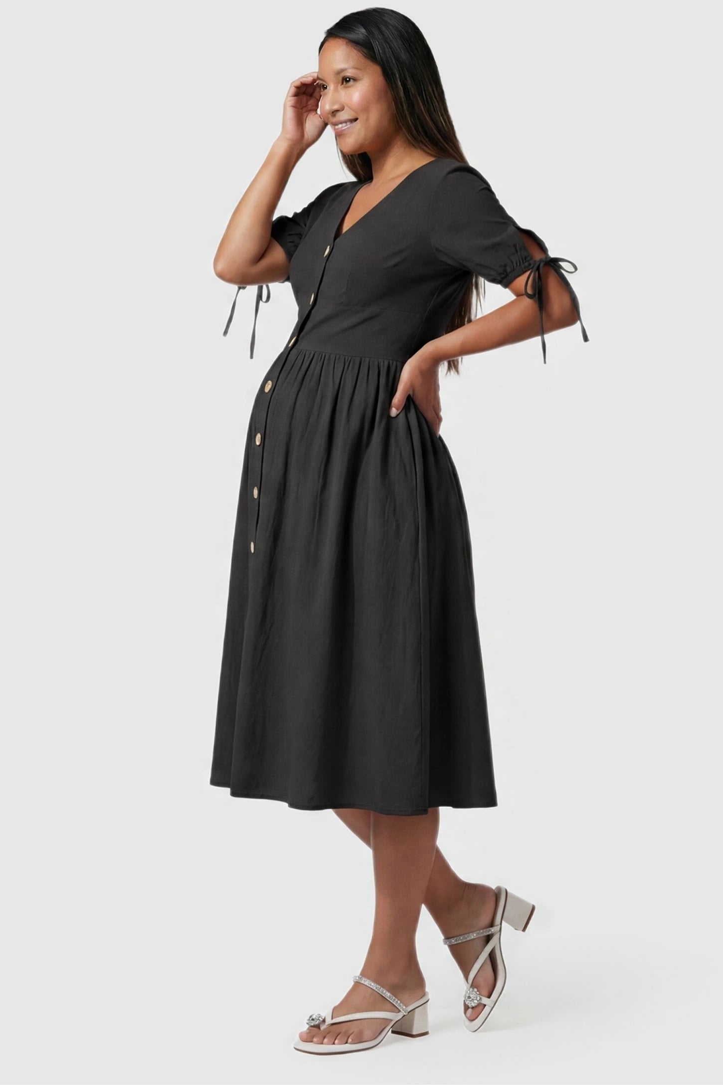 Tie-Sleeve V-Neck Flared Maternity Midi Dress Side view Tie-Sleeve V-Neck Flared Maternity Midi Dress in Black featuring an empire waist on a pregnant model.