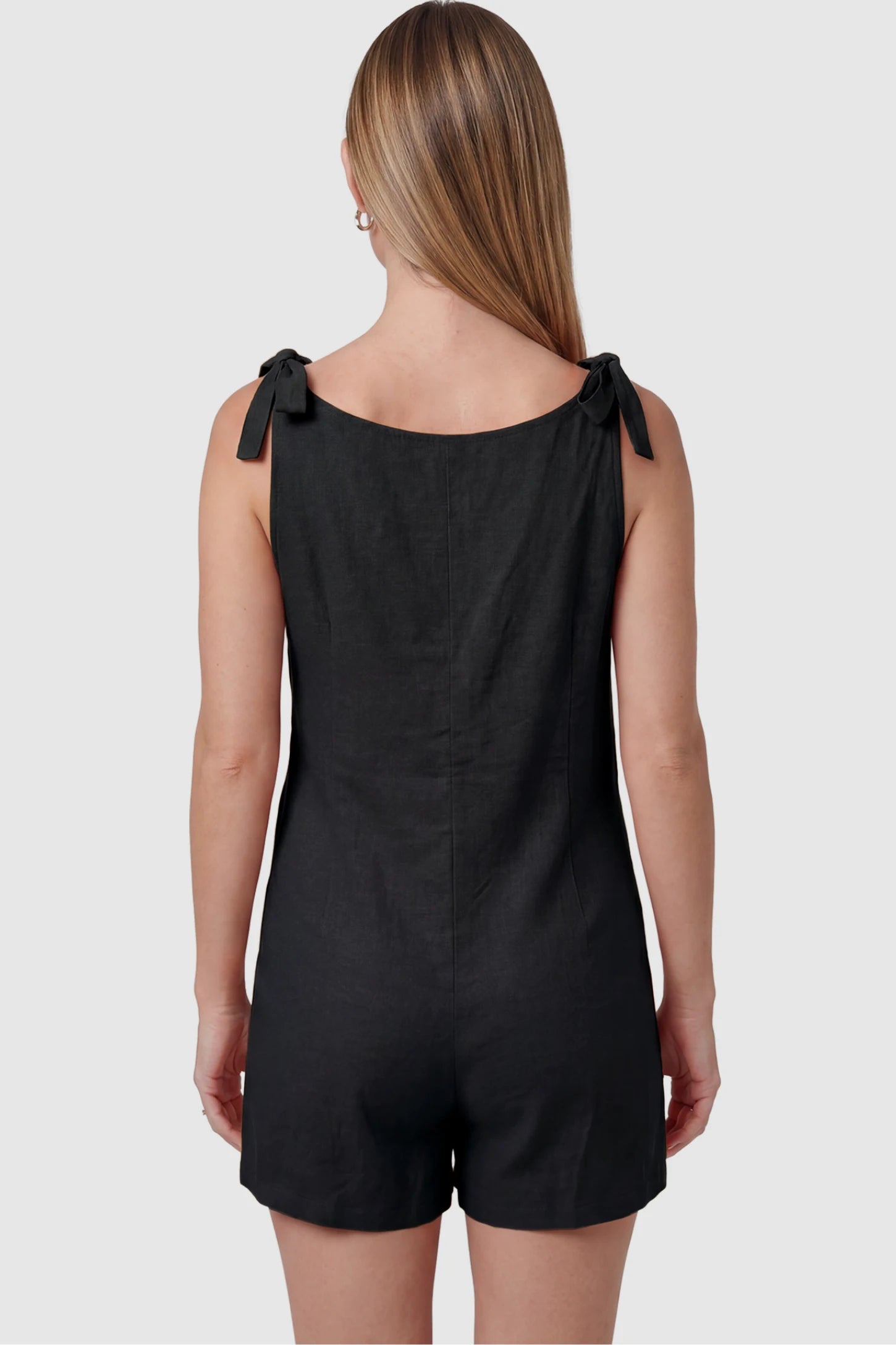 Tie-Strap Sleeveless Pocketed Maternity Romper Tie-strap sleeveless pocketed maternity romper in black with adjustable tie straps, back view on pregnant model