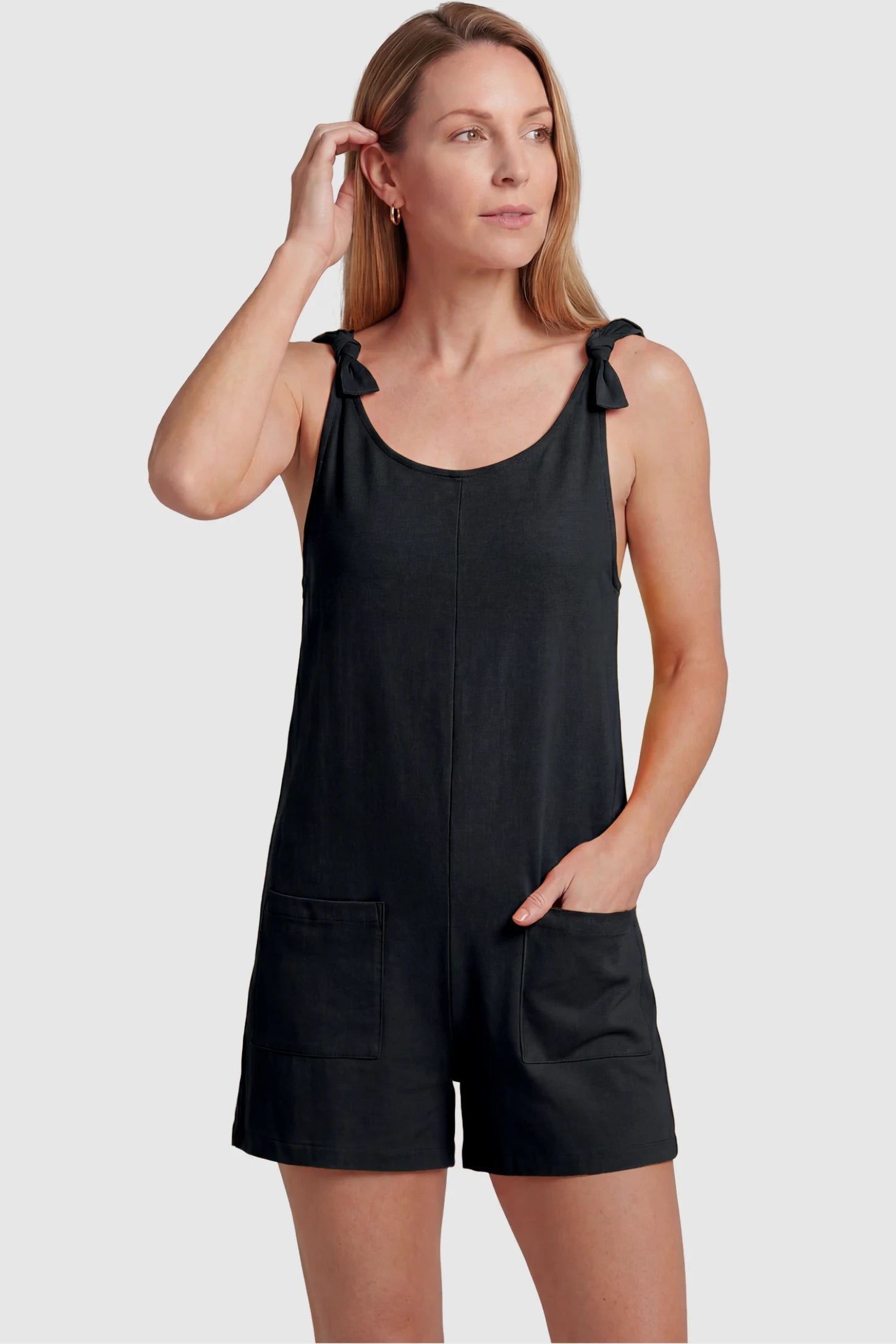 Tie-Strap Sleeveless Pocketed Maternity Romper Tie-strap sleeveless pocketed maternity romper in black with adjustable tie straps and scoop neckline, front view on postpartum model
