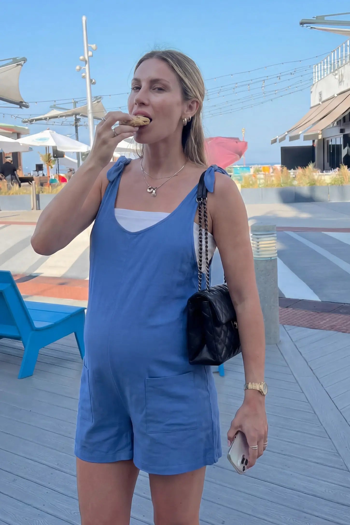 Tie-Strap Sleeveless Pocketed Maternity Romper Tie-strap sleeveless pocketed maternity romper in blue with adjustable tie straps and scoop neckline, front view on pregnant model