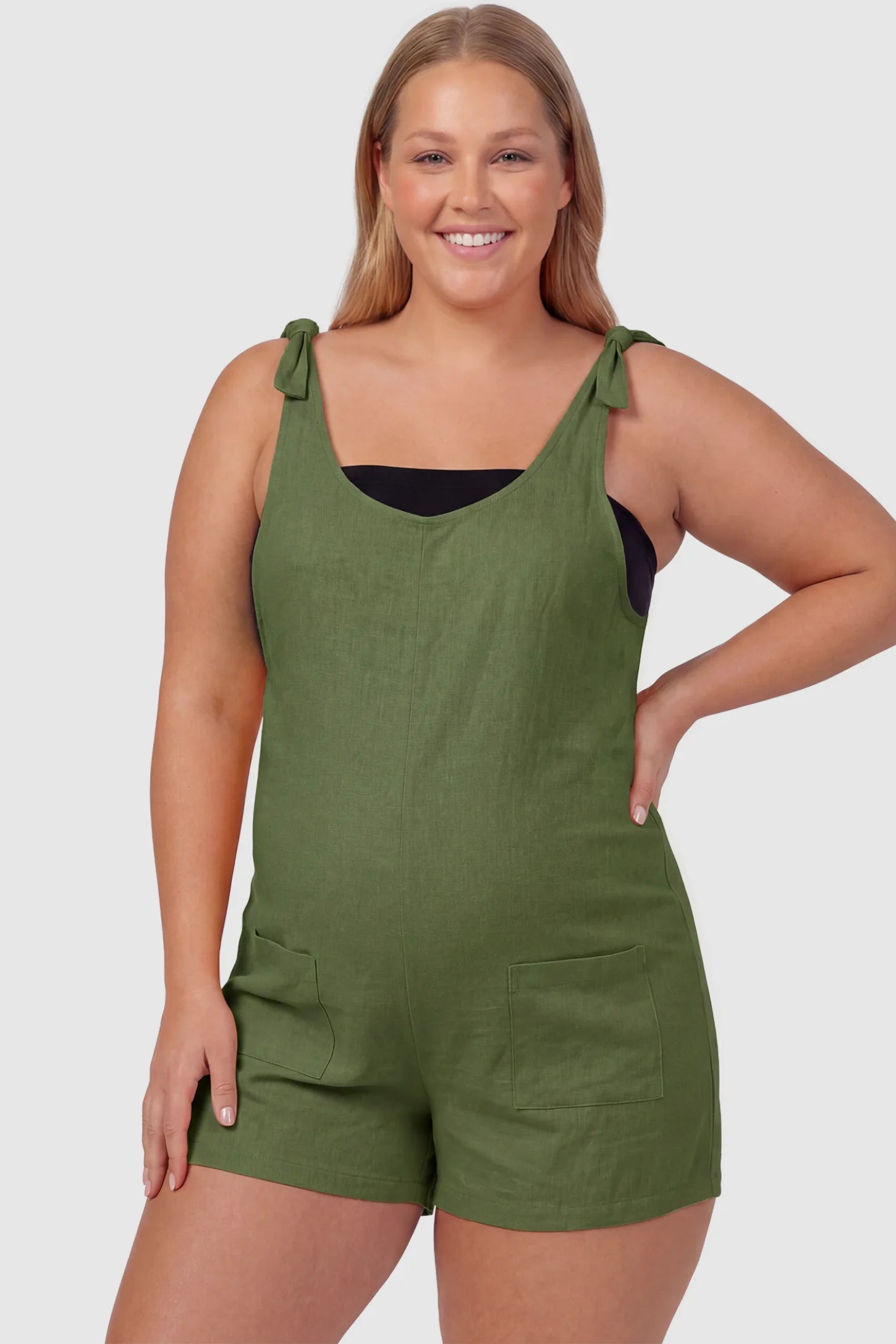 Tie-Strap Sleeveless Pocketed Maternity Romper Tie-strap sleeveless pocketed maternity romper in green with adjustable tie straps and scoop neckline, front view on plus-size model