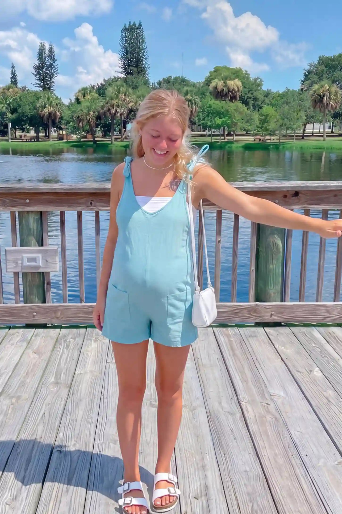 Tie-Strap Sleeveless Pocketed Maternity Romper Tie-strap sleeveless pocketed maternity romper in sky blue with adjustable tie straps and scoop neckline, front view on pregnant model