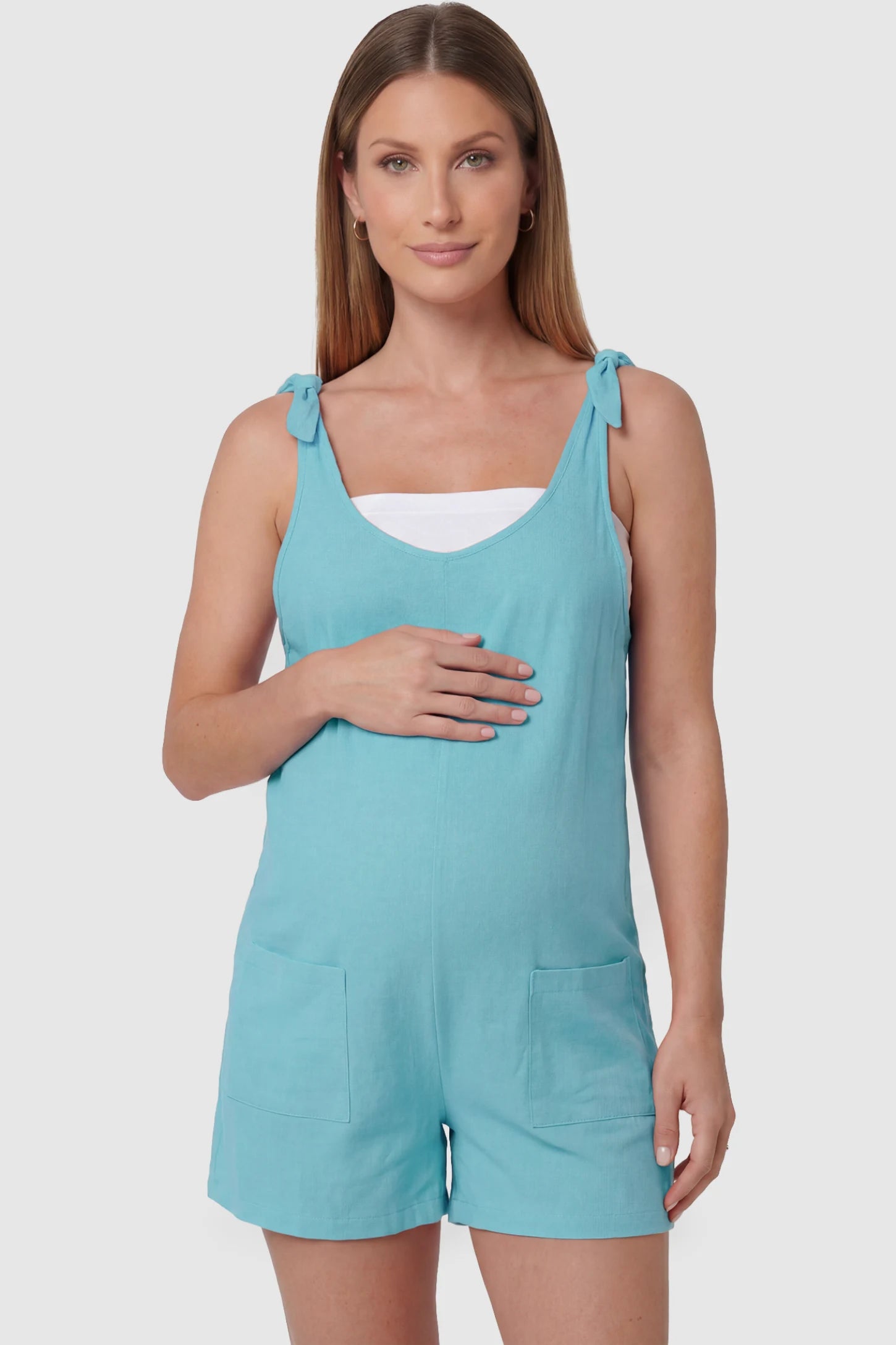 Tie-Strap Sleeveless Pocketed Maternity Romper Tie-strap sleeveless pocketed maternity romper in sky blue with adjustable tie straps and scoop neckline, front view on pregnant model