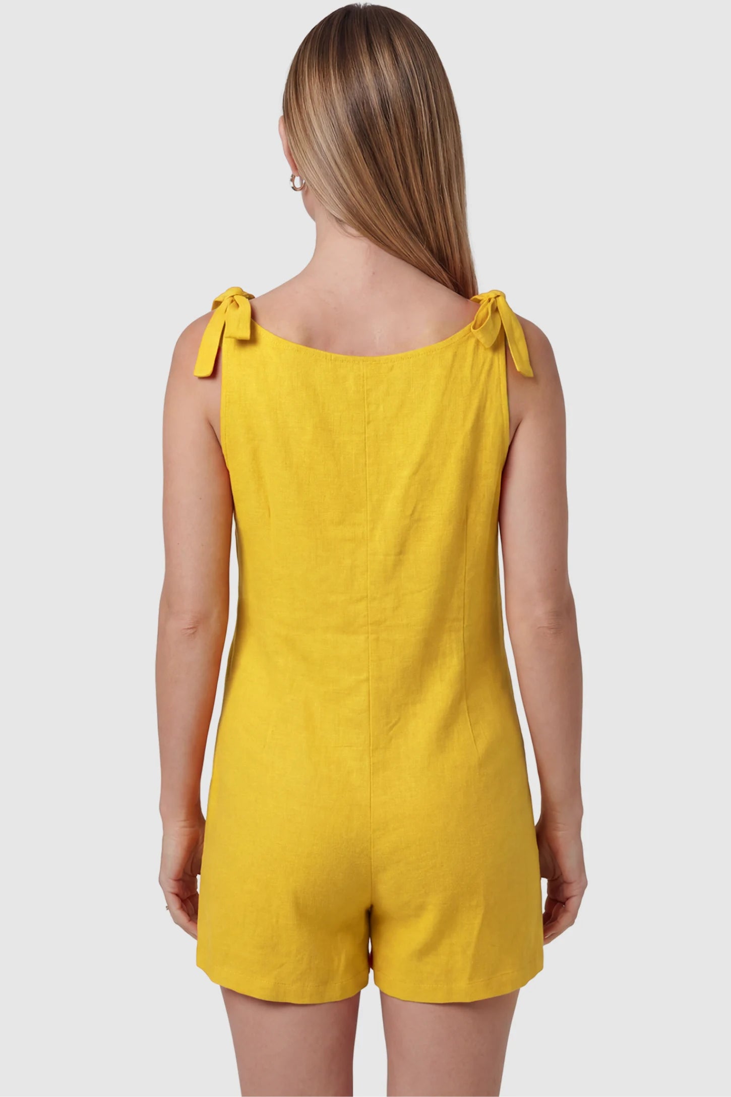 Tie-Strap Sleeveless Pocketed Maternity Romper Tie-strap sleeveless pocketed maternity romper in yellow with adjustable tie straps, back view on pregnant model
