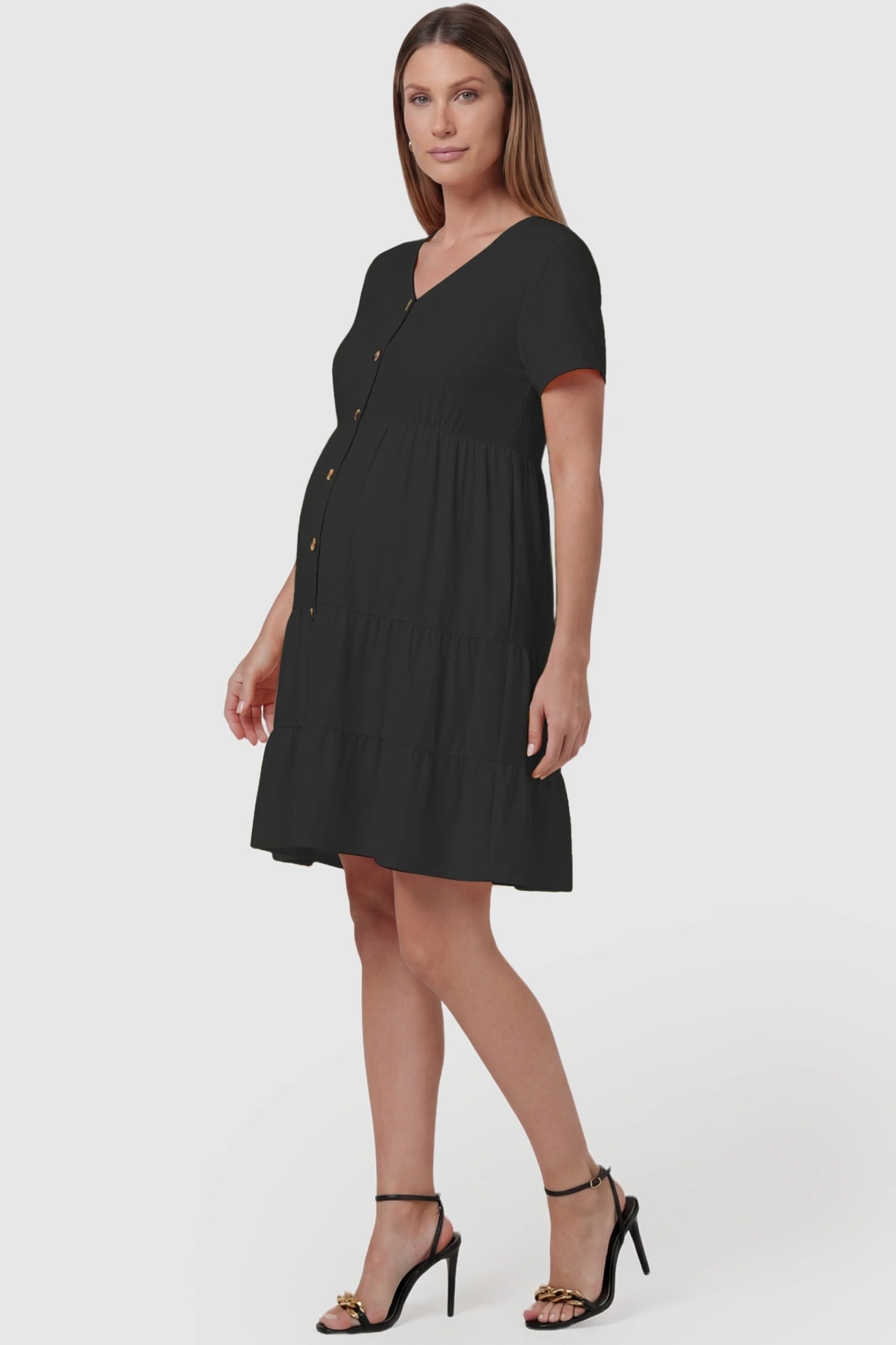 Tiered Button-Front A-Line Maternity Summer Dress Tiered Button-Front A-Line Maternity Summer Dress in Black featuring an elasticized high waist on a pregnant model, side view.