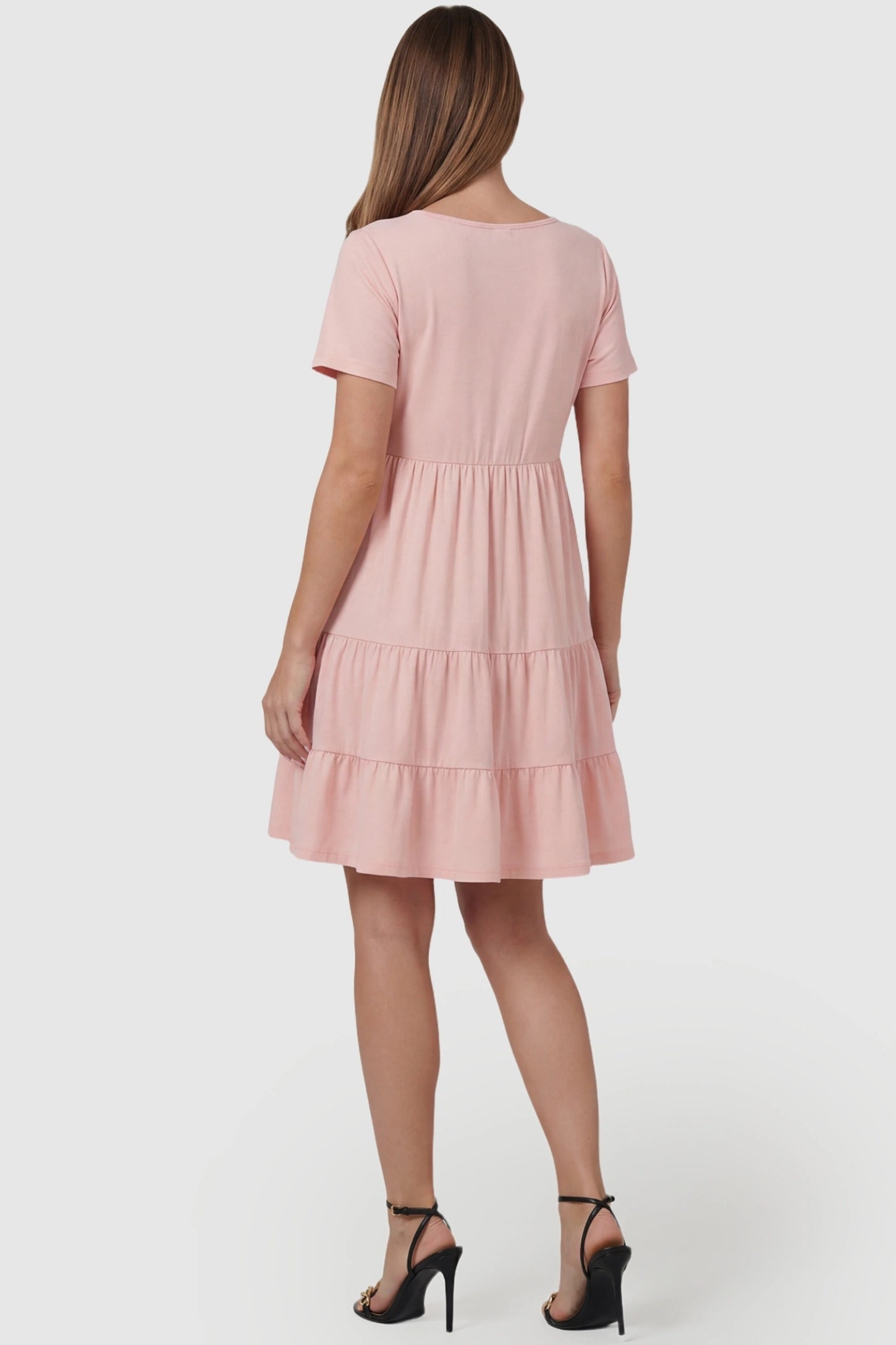 Tiered Button-Front A-Line Maternity Summer Dress Tiered Button-Front A-Line Maternity Summer Dress in Pink featuring a high-waist tiered silhouette on a pregnant model, back view.