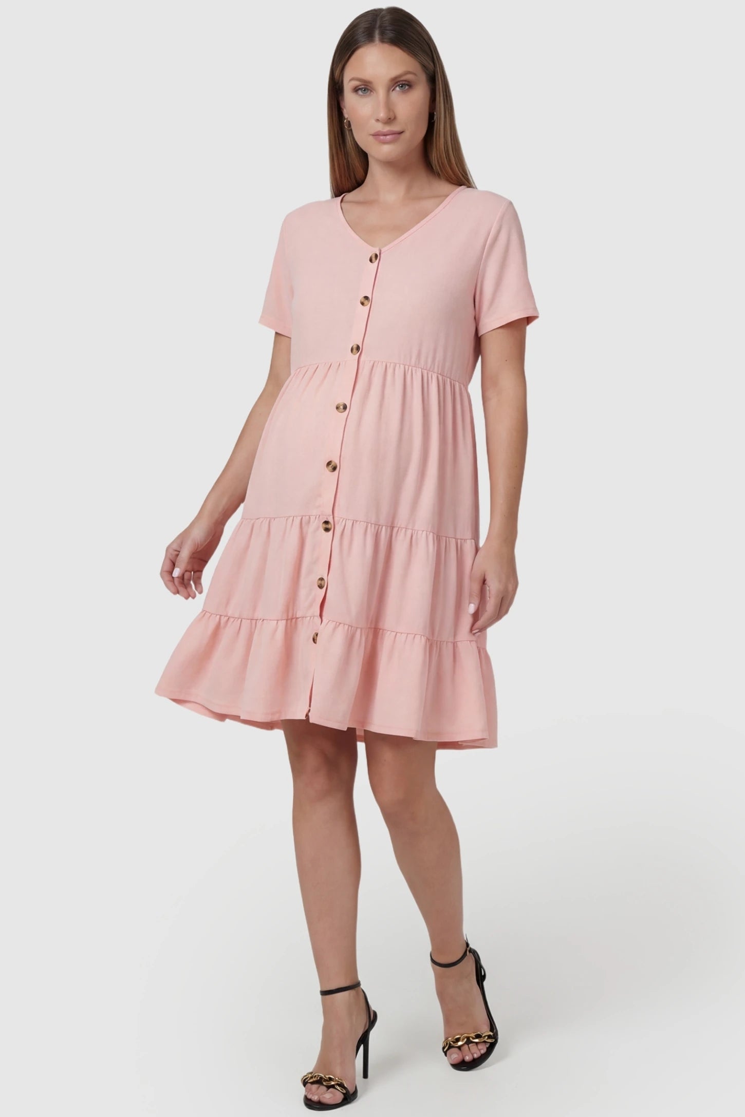 Tiered Button-Front A-Line Maternity Summer Dress in Pink featuring a ruffled hem on a pregnant model, front view.