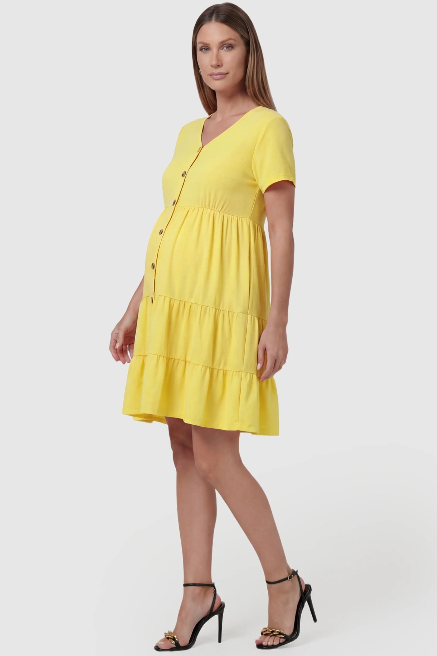 Tiered Button-Front A-Line Maternity Summer Dress Tiered Button-Front A-Line Maternity Summer Dress in Yellow featuring a fresh summer aesthetic on a pregnant model, side view.