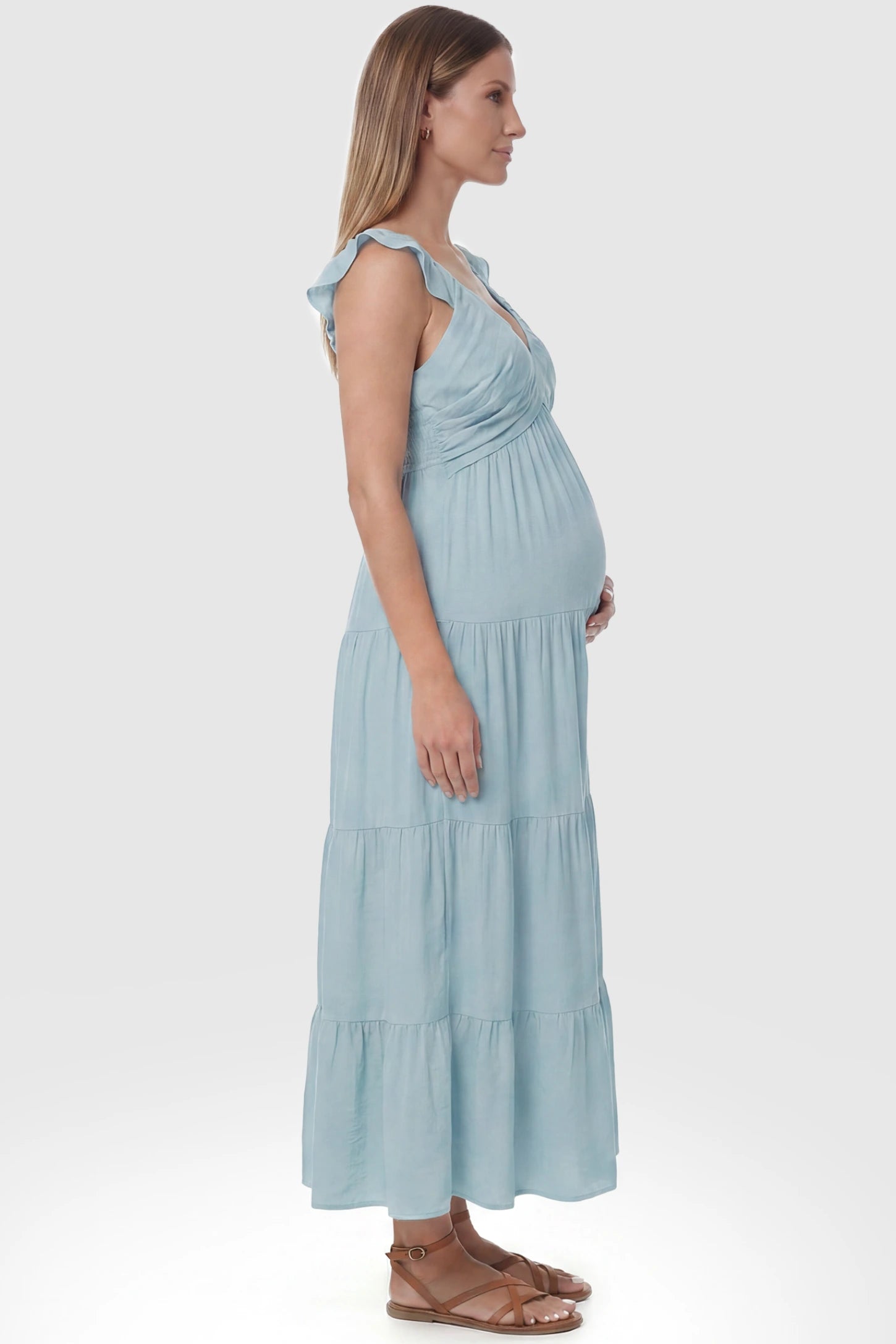 Ruffled Sleeve V-neck A-line Maternity Midi Dress Ruffled sleeve V-neck A-line maternity midi dress in blue with ruffled sleeves and tiered skirt, side view on pregnant model